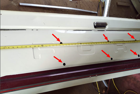Outside of a 1987-1996 Ford tailgate with arrows marking the six 3/4 inch trim panel bracket holes and a tape measure across it