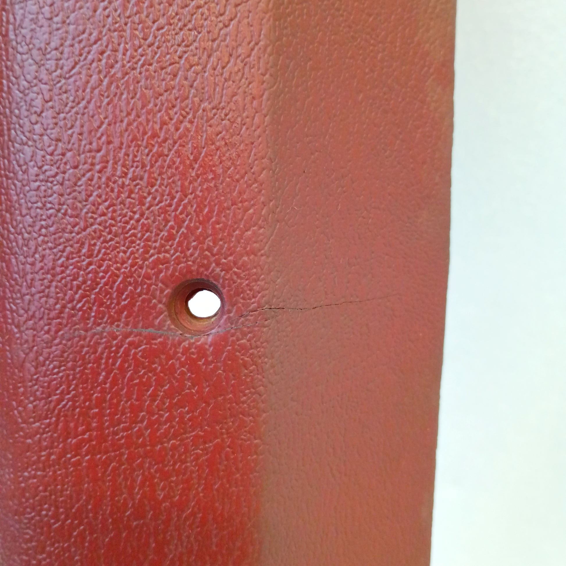 Red A-pillar trim piece for 1980-1986 Ford Bronco and F-series trucks, showing a small crack near a mounting hole.