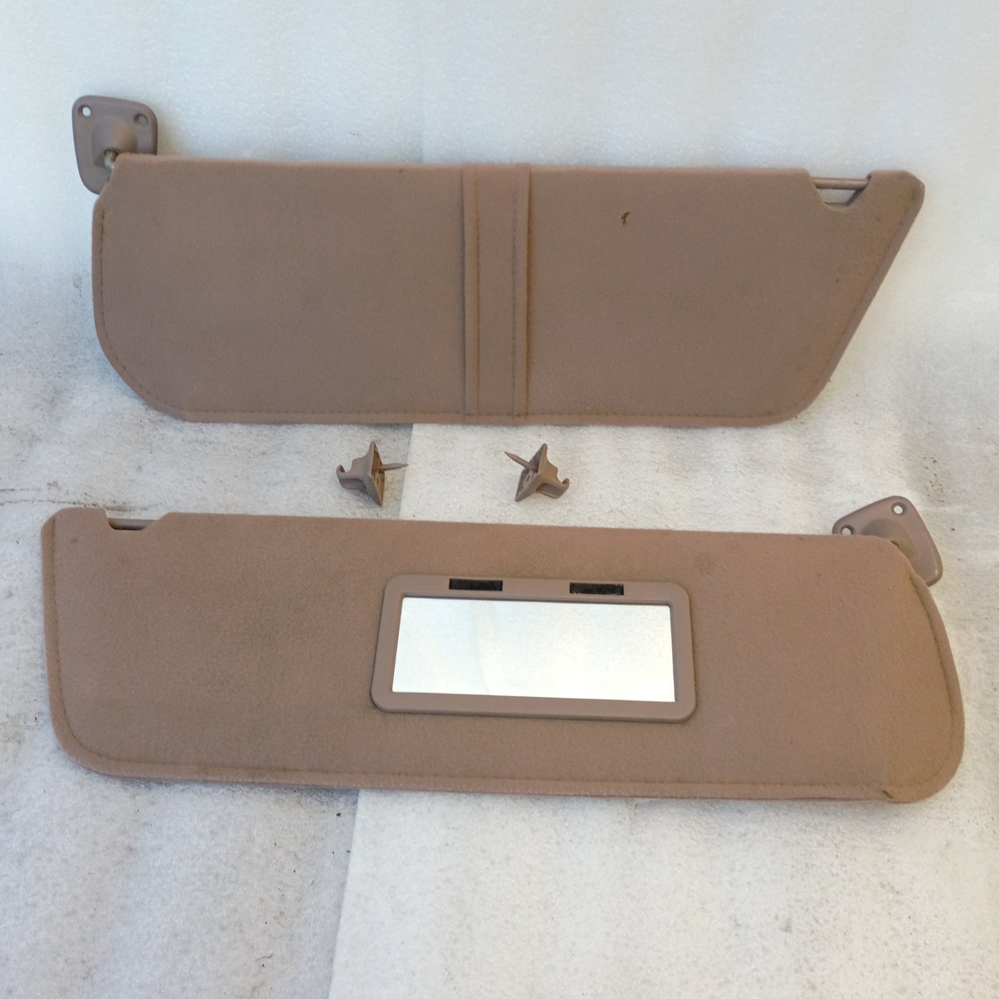 Tan/mocha cloth sun visors for Ford vehicles, including hinges and swivel mounts. Passenger side has vanity mirror.