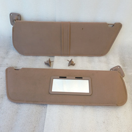 Tan/mocha cloth sun visors for Ford vehicles, including hinges and swivel mounts. Passenger side has vanity mirror.