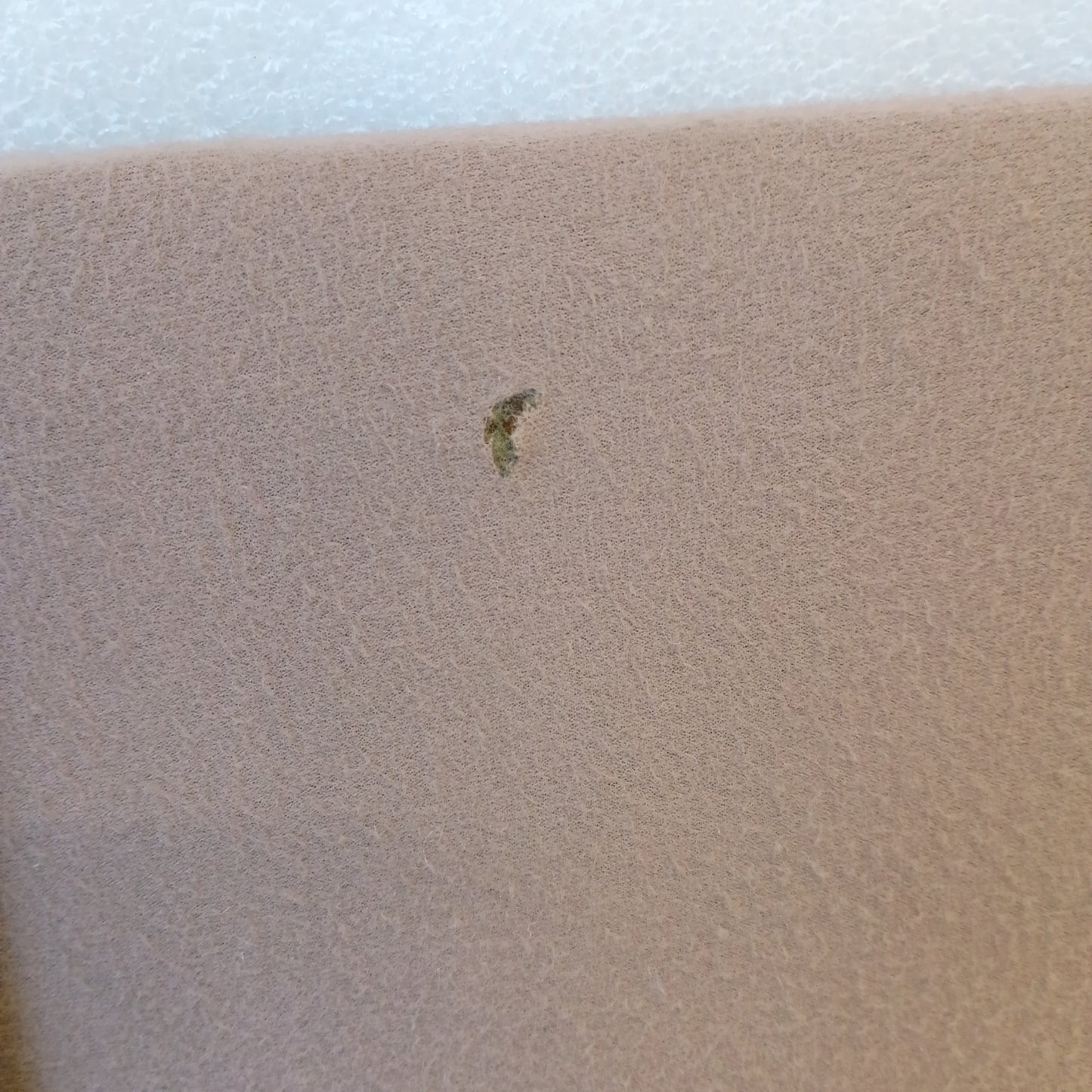 Close-up of tan/mocha cloth with a small mark, part of a 1992-1997 Ford sun visor for F150, F250, F350, Bronco.