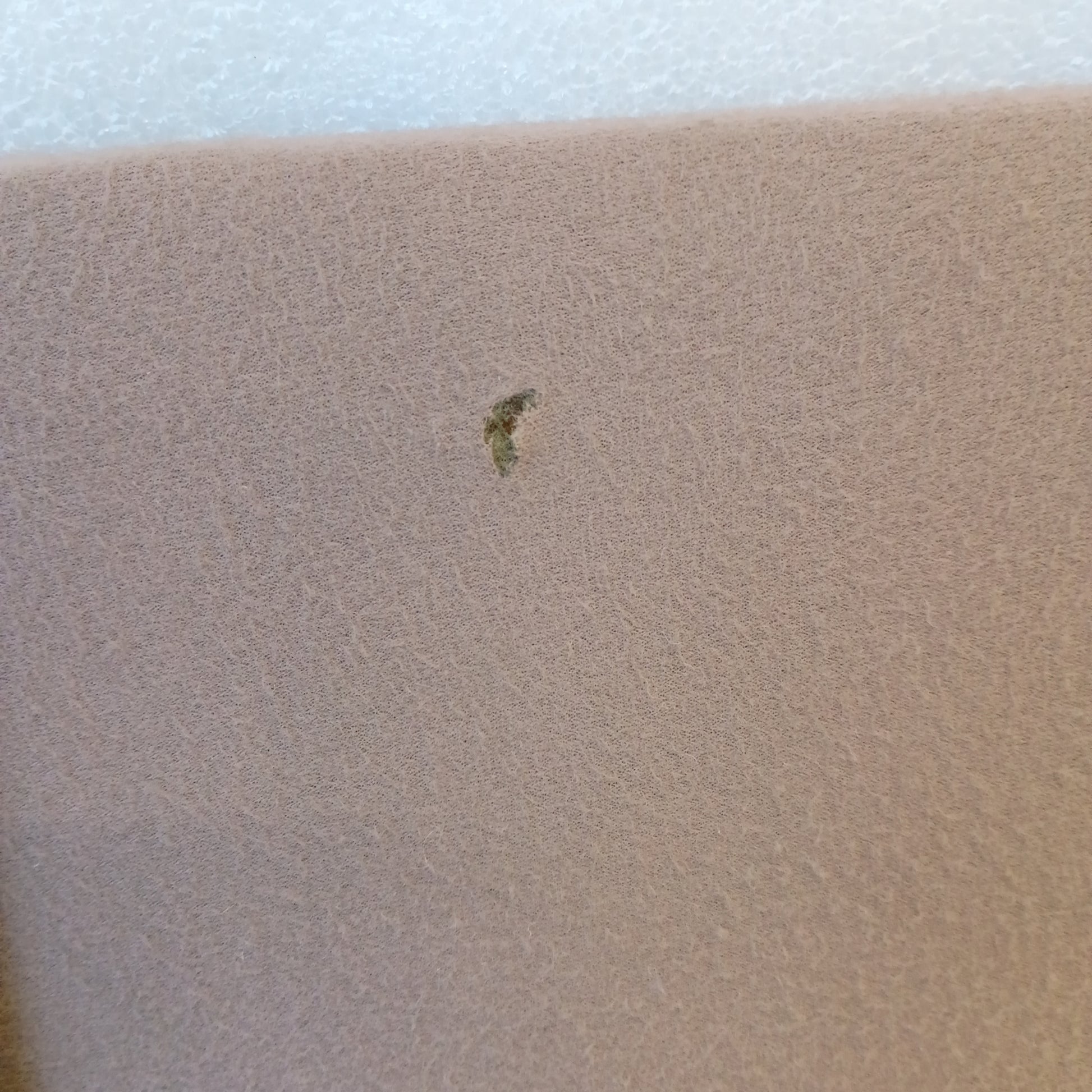 Close-up of tan/mocha cloth with a small mark, part of a 1992-1997 Ford sun visor for F150, F250, F350, Bronco.