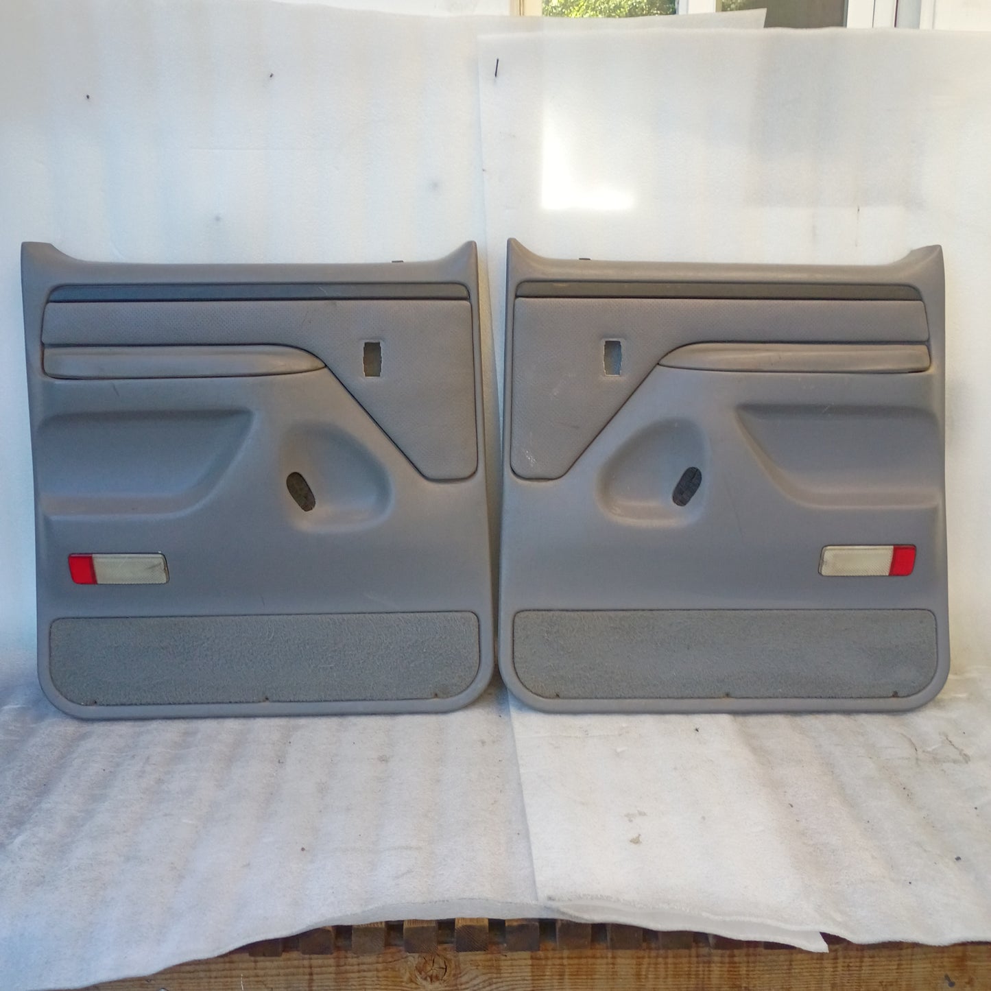 Left and right deluxe light gray rear door panels for 1992-1997 Ford F250/F350. Includes armrests and red reflectors.