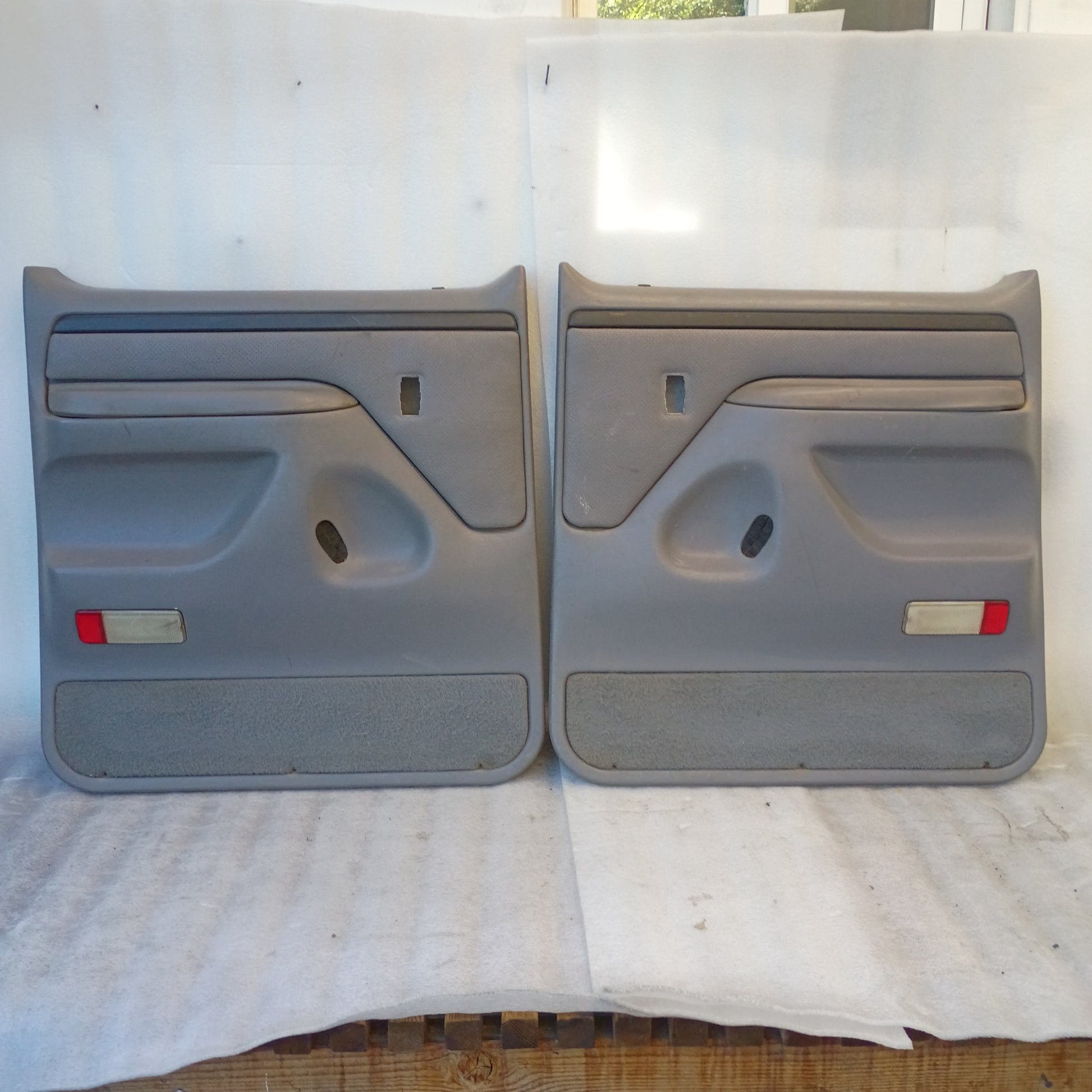 Left and right deluxe light gray rear door panels for 1992-1997 Ford F250/F350. Includes armrests and red reflectors.