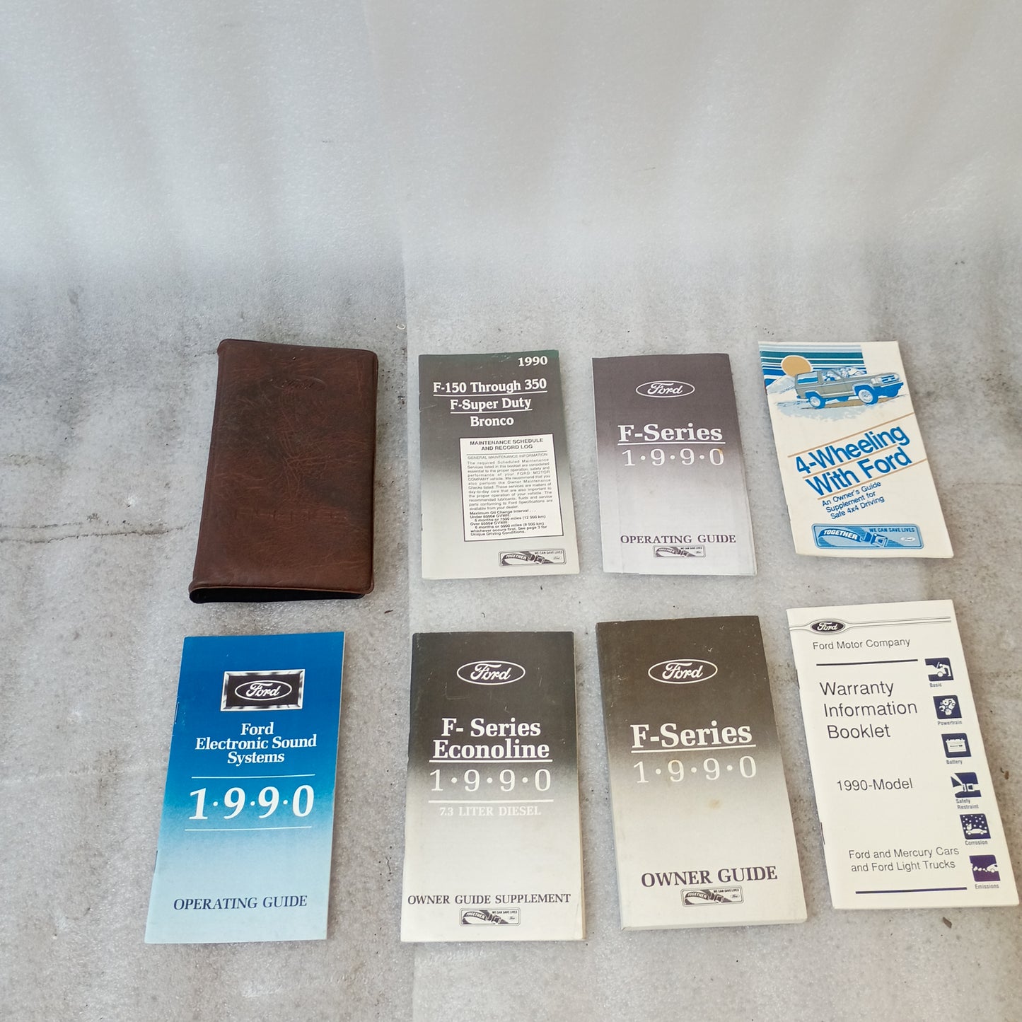 1990 Ford F-Series manuals set including operating guides, maintenance schedule, 7.3L Diesel supplement, and brown case.