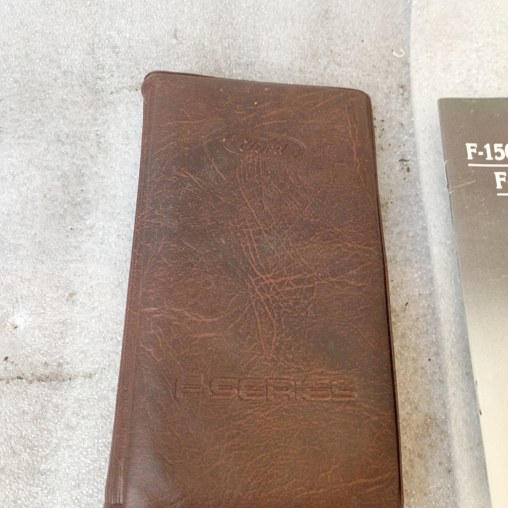 Brown vinyl padded cover of a 1990 Ford F-Series manual set with embossed "F-Series" text.