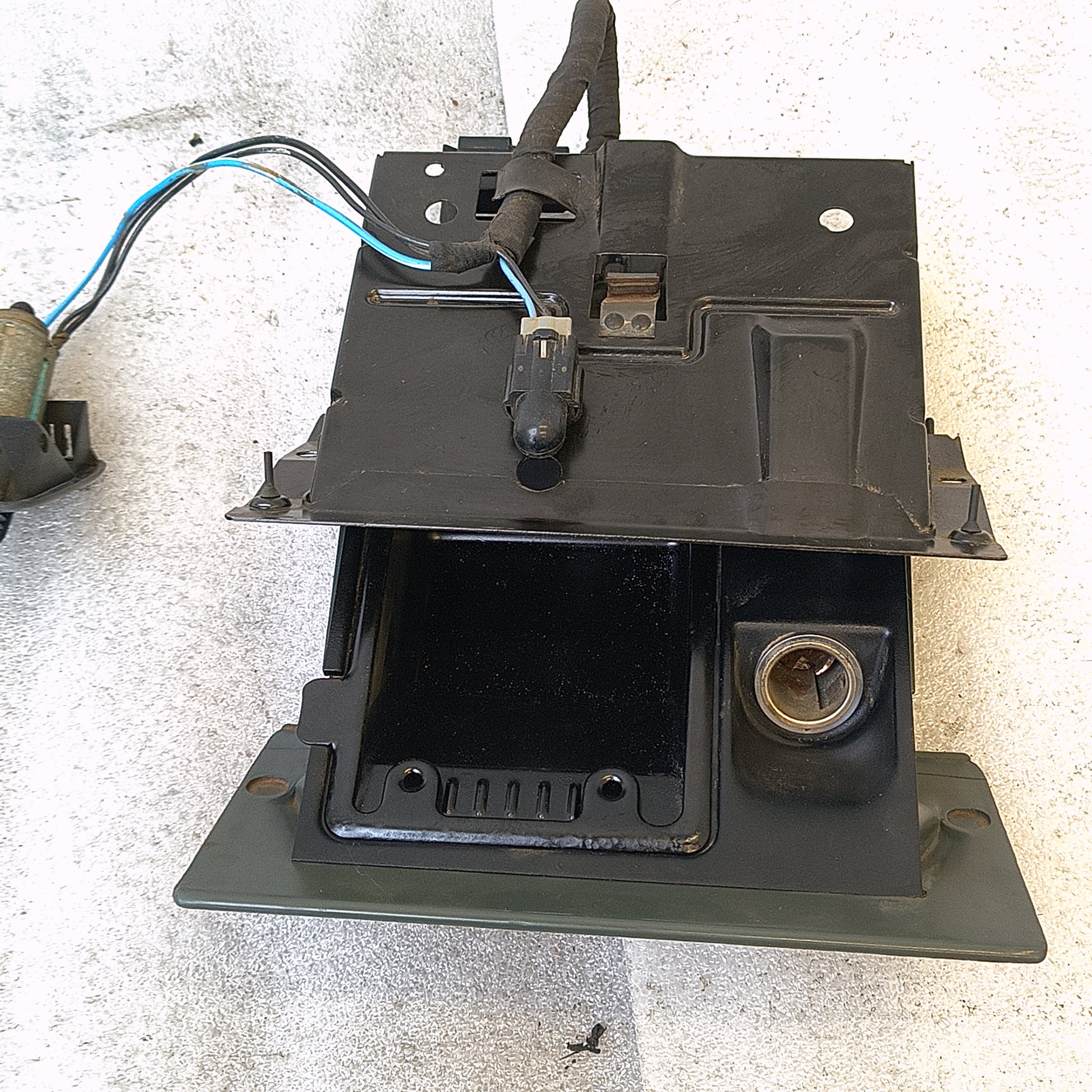 Dark gray ashtray assembly with power port and wire harness for 1992-1996 Ford F150-F350 and Bronco. Includes mounting bracket.