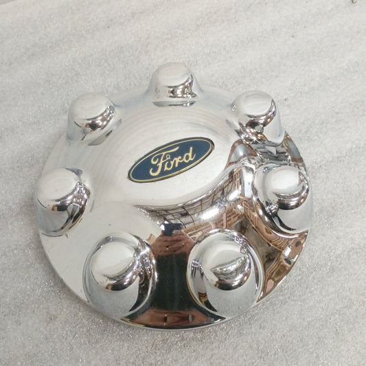 Chrome Ford 7-lug center cap with Ford logo, compatible with 1999-2004 F-250/F-350 Super Duty, minor scratches visible.