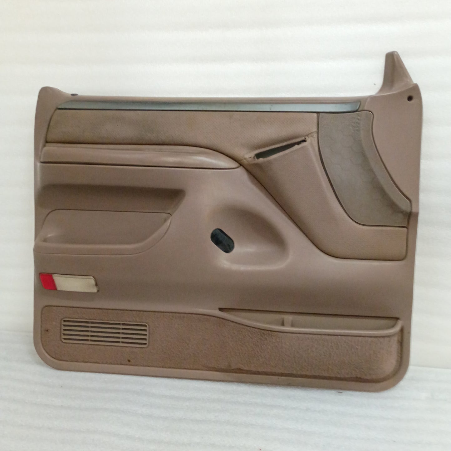Tan Ford F150-F350 Bronco door panel, silver trim, red reflector, and visible wear on top edge, for power windows and locks.