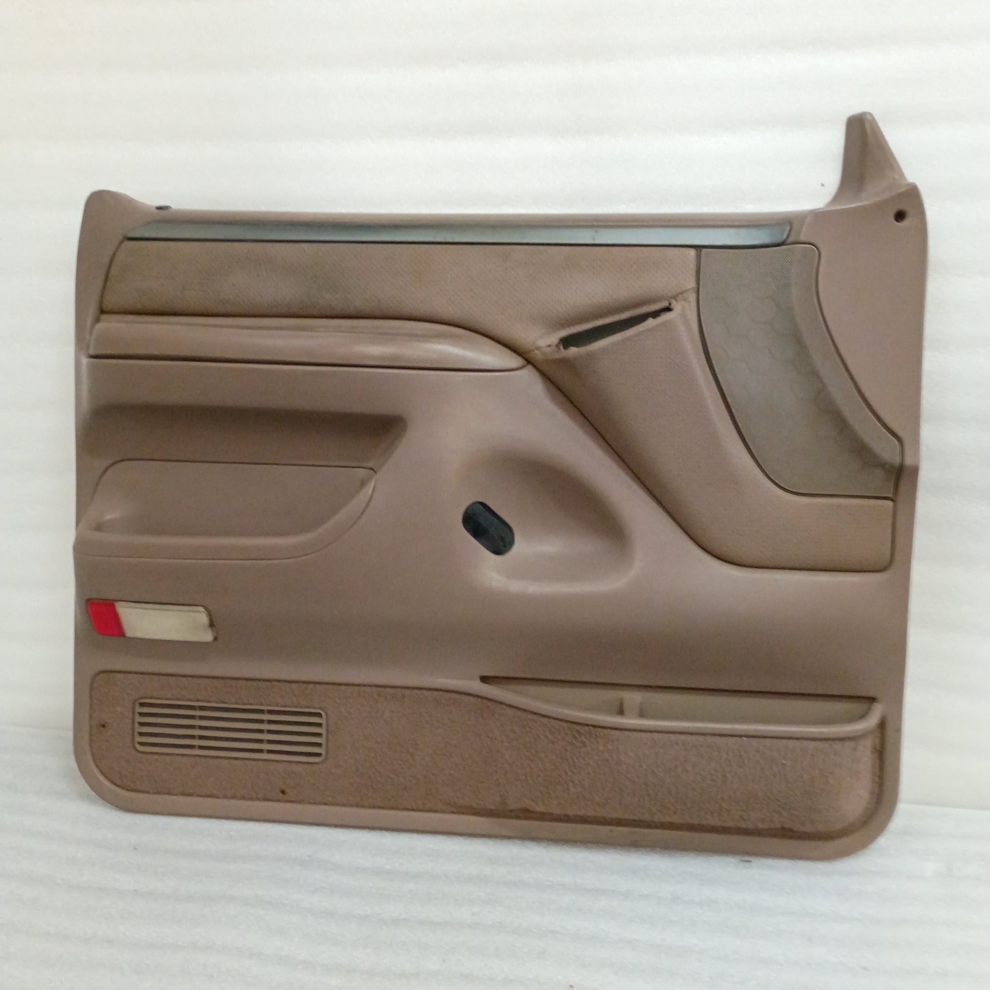 Tan Ford F150-F350 Bronco door panel, silver trim, red reflector, and visible wear on top edge, for power windows and locks.