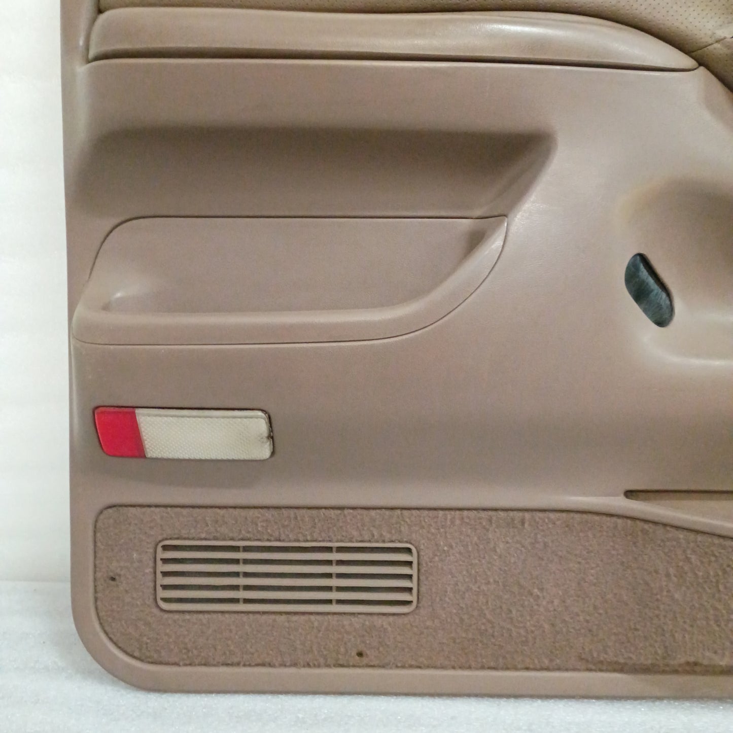 Tan door panel for Ford F150/F250/F350/Bronco, 1992-1997, with red reflector, map pocket carpet, and speaker grill.