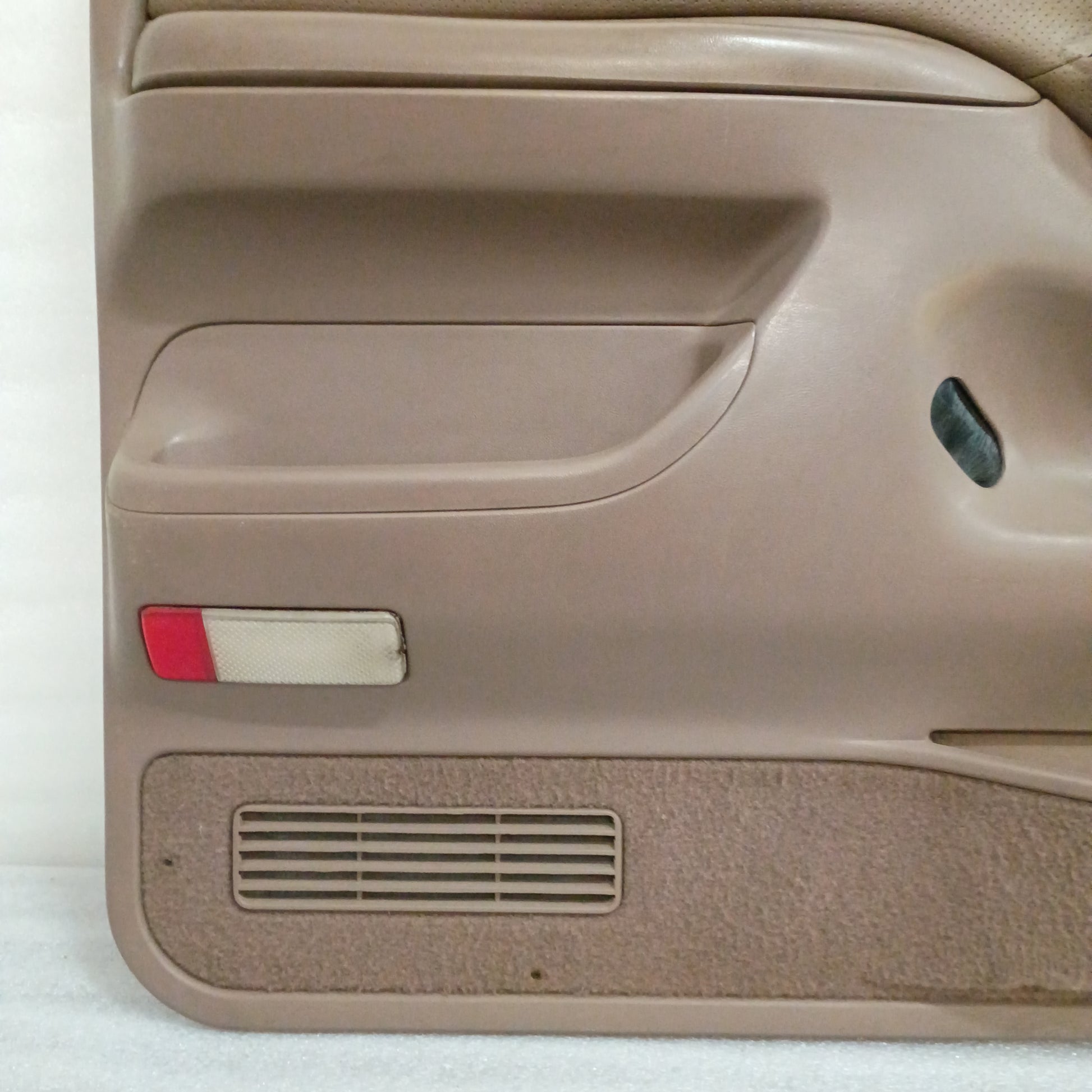 Tan door panel for Ford F150/F250/F350/Bronco, 1992-1997, with red reflector, map pocket carpet, and speaker grill.