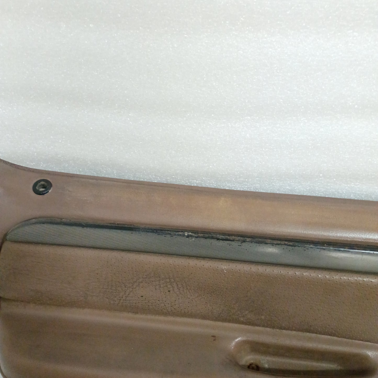 Tan door panel for Ford trucks and Bronco, featuring a silver and black trim strip, with minor wear on the top edge.