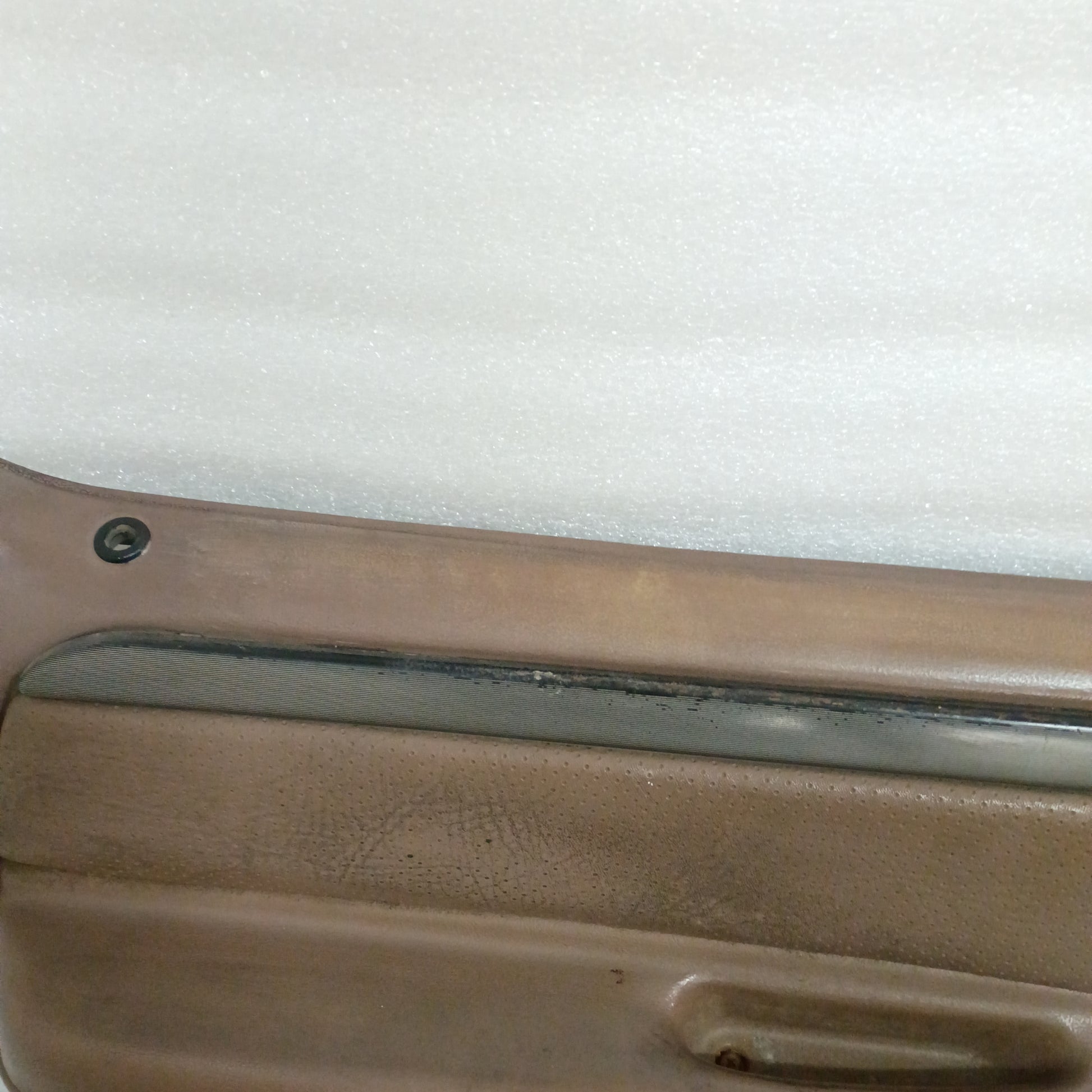 Tan door panel for Ford trucks and Bronco, featuring a silver and black trim strip, with minor wear on the top edge.