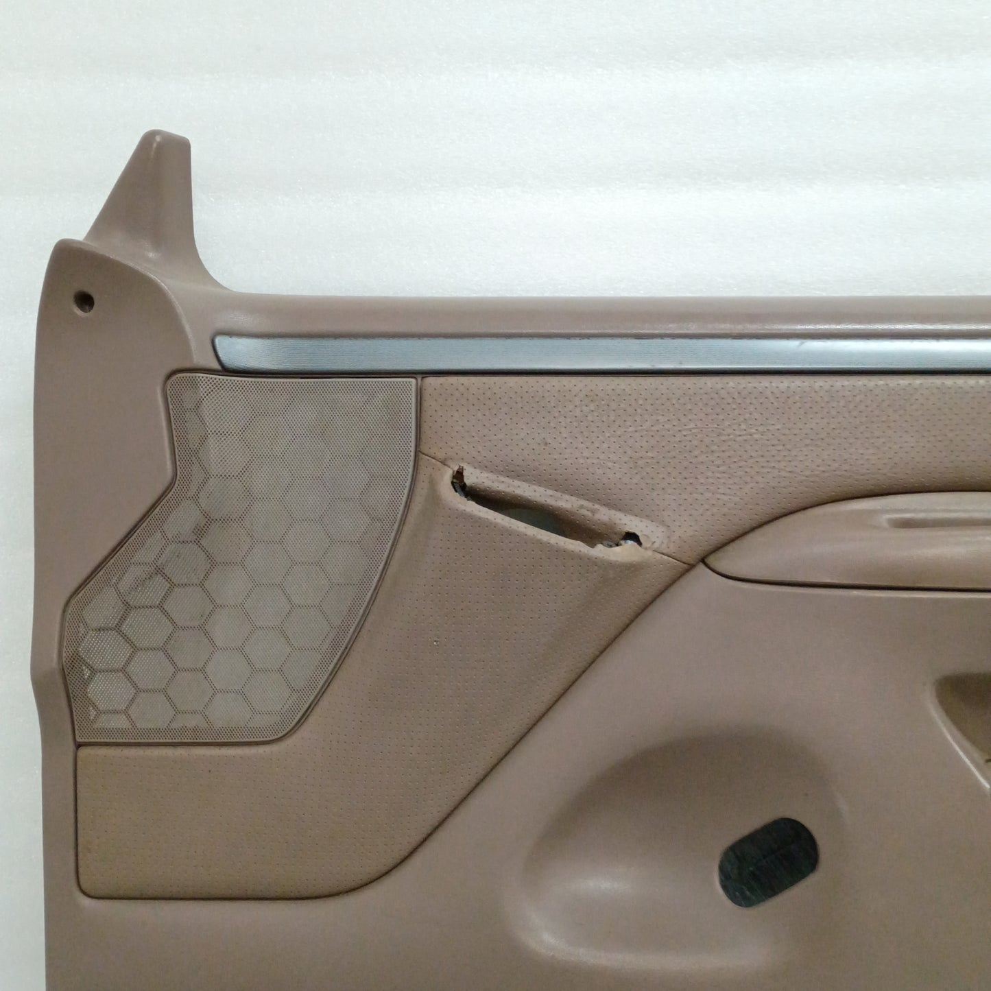 Tan Ford F150/F250/F350/Bronco door panel, silver trim, vinyl armrest, honeycomb speaker grill, minor wear top edge.