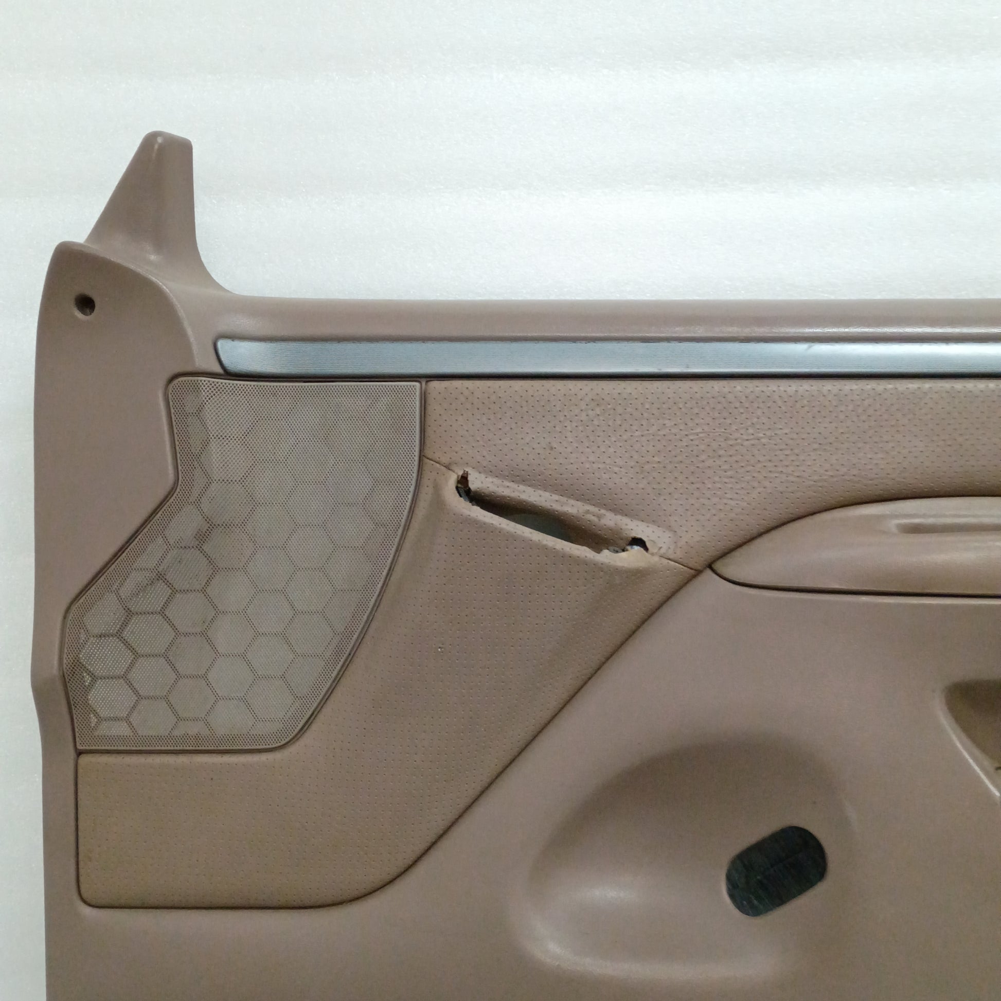 Tan Ford F150/F250/F350/Bronco door panel, silver trim, vinyl armrest, honeycomb speaker grill, minor wear top edge.