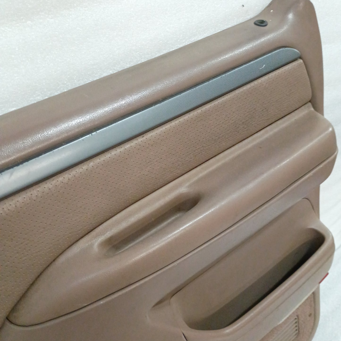 Tan deluxe door panel for Ford trucks (1992-1997), featuring silver trim and door handle, with minor wear visible.