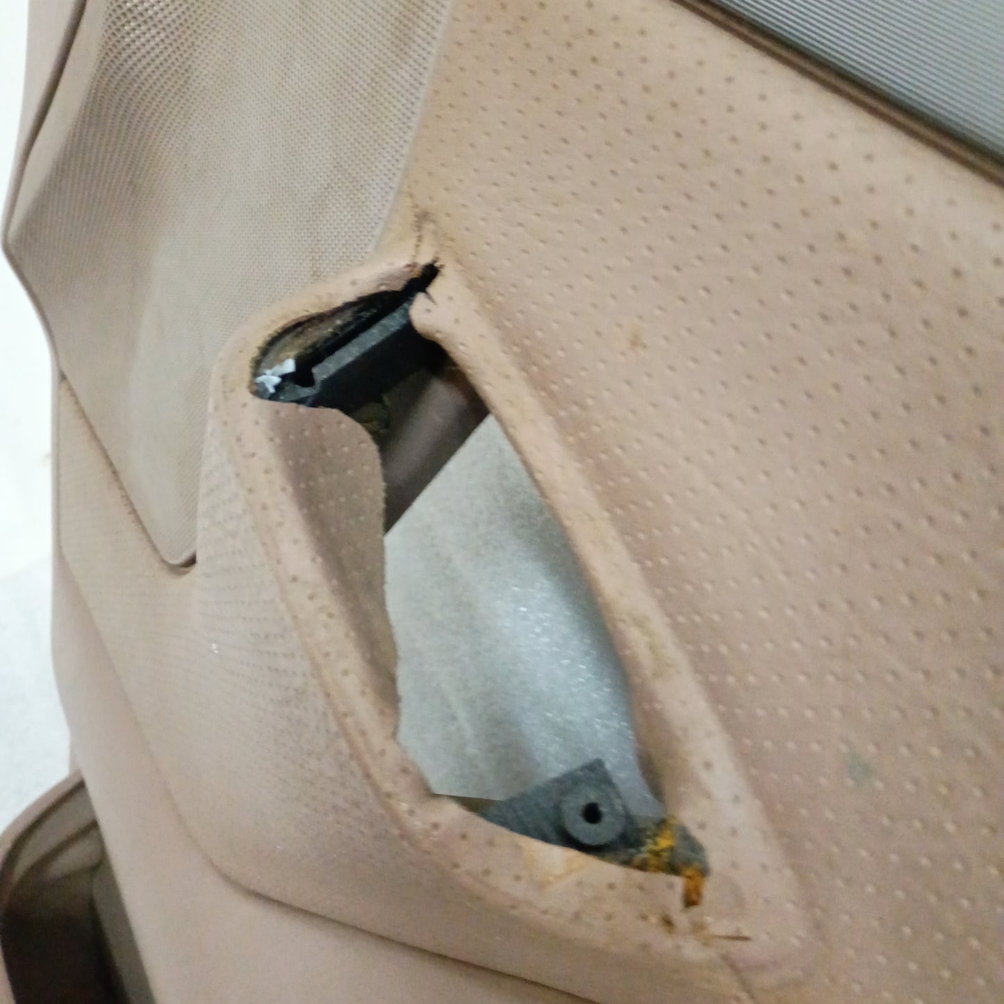 Tan Ford door panel with visible wear near the handle cutout, featuring textured surfaces and slight discoloration.