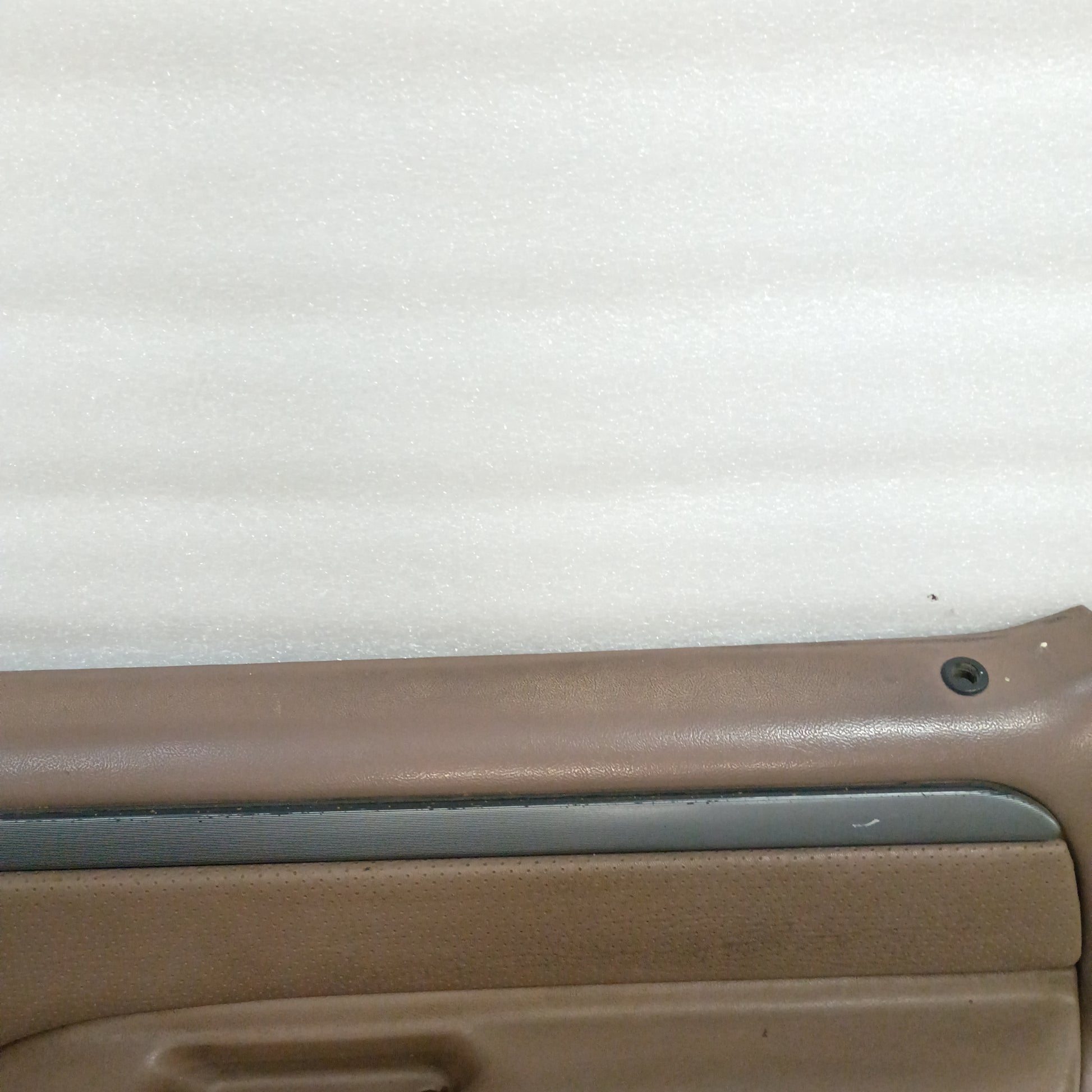 Tan door panel for 1992-1997 Ford trucks, featuring silver trim with black lines and minor wear on the top edge.