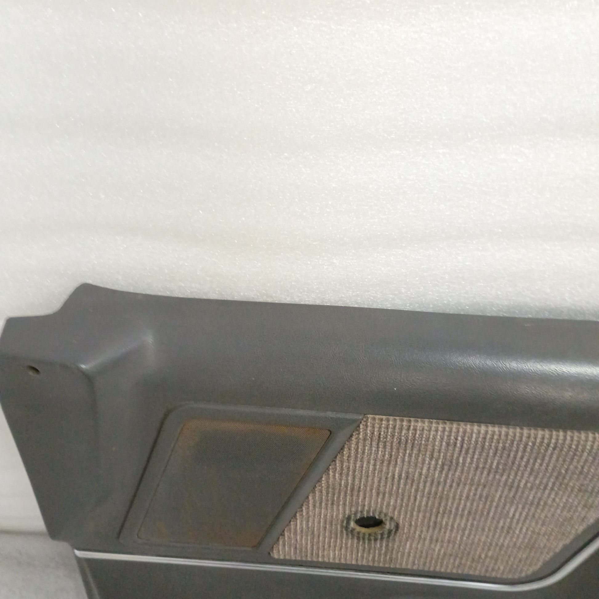 Dark gray Ford door panel for manual windows, features a carpeted map pocket, speaker grille in good condition, compatible with 1987-1991 F150/F250/F350/Bronco.