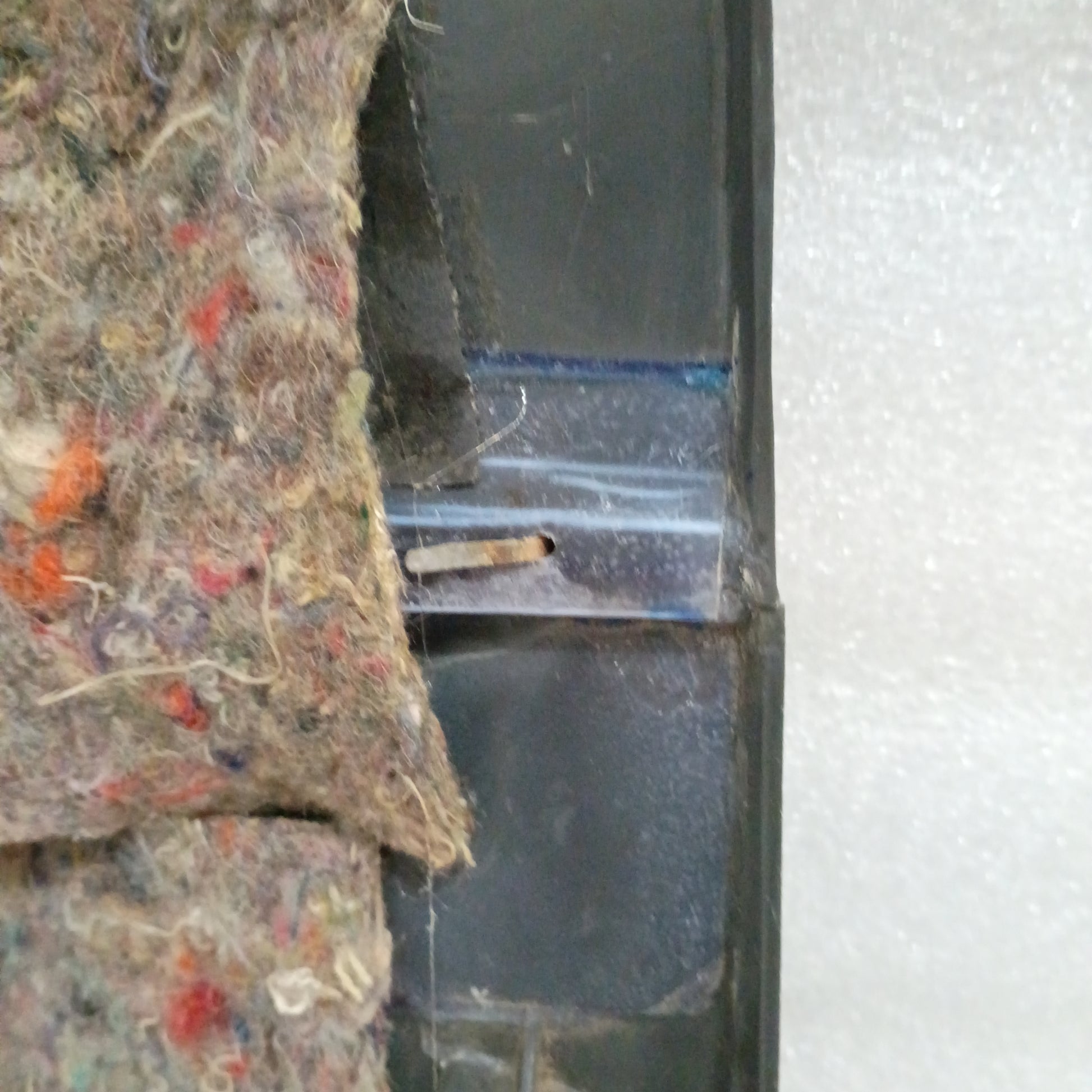 Close-up of textured carpeted map pocket insert and plastic detail from a Ford deluxe dark gray door panel.