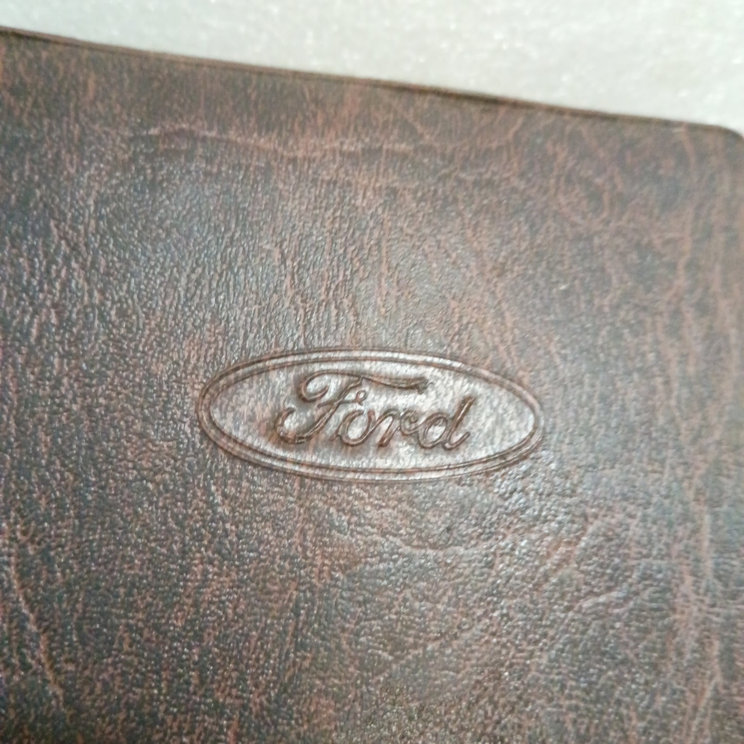 Embossed Ford logo on a worn brown leather cover, part of 1996 F-Series Owner Guide for Ford F-150, F-250, F-350.