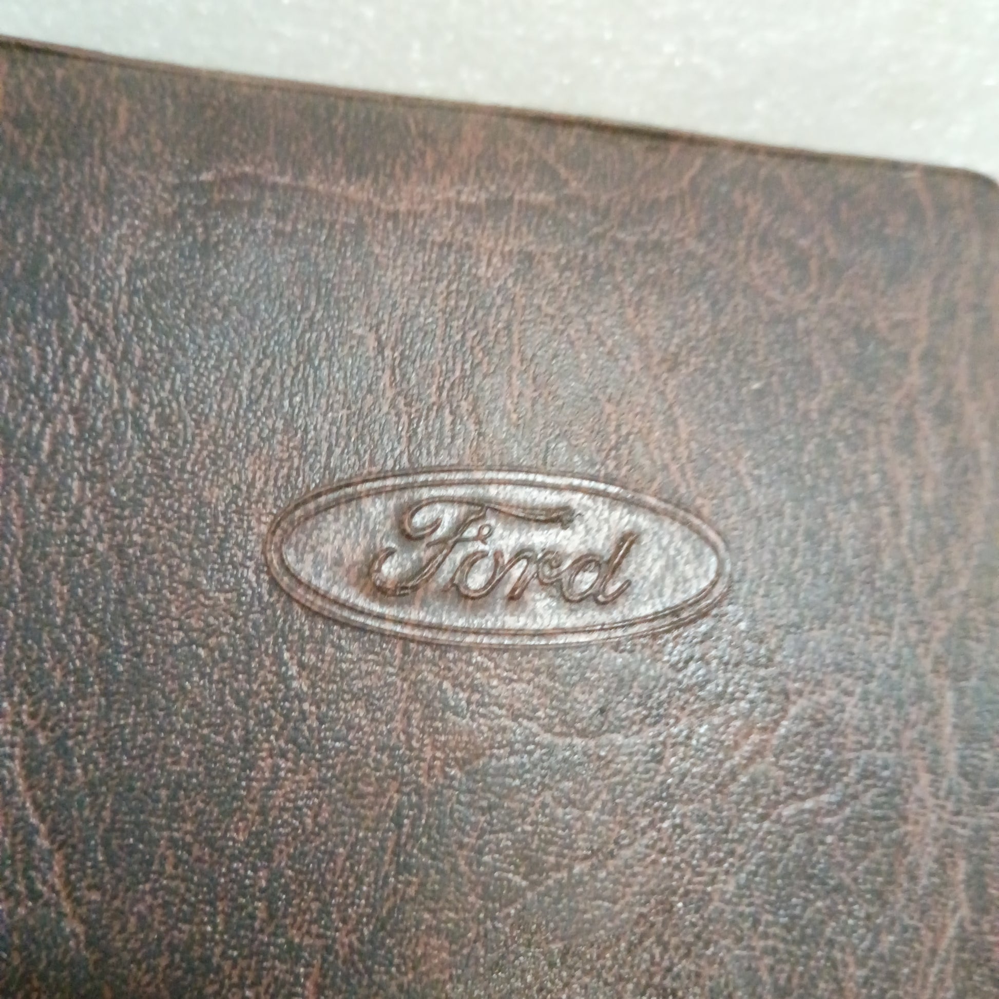 Embossed Ford logo on a worn brown leather cover, part of 1996 F-Series Owner Guide for Ford F-150, F-250, F-350.