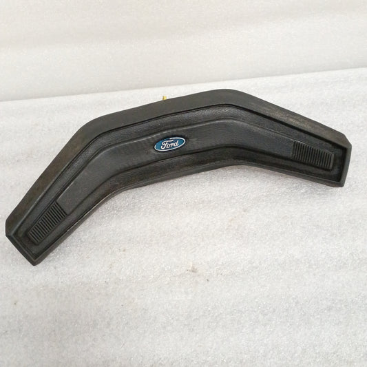 Black Ford OEM steering wheel horn button with central logo, vinyl grain pattern, and worn corners. Fits 80-86 F150, F250, F350, Bronco.
