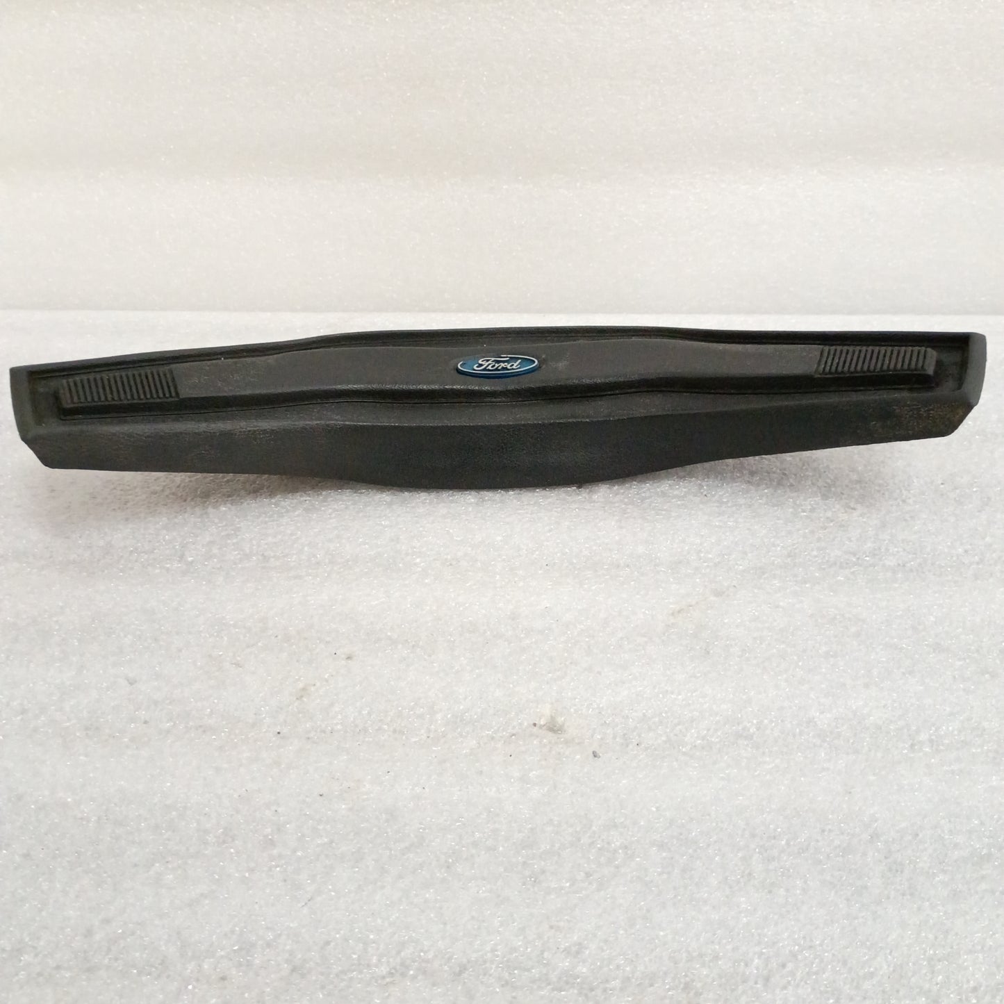 Black Ford steering wheel horn button with logo, vinyl grain pattern, slightly worn corners. Compatible with F150, F250, F350, Bronco.