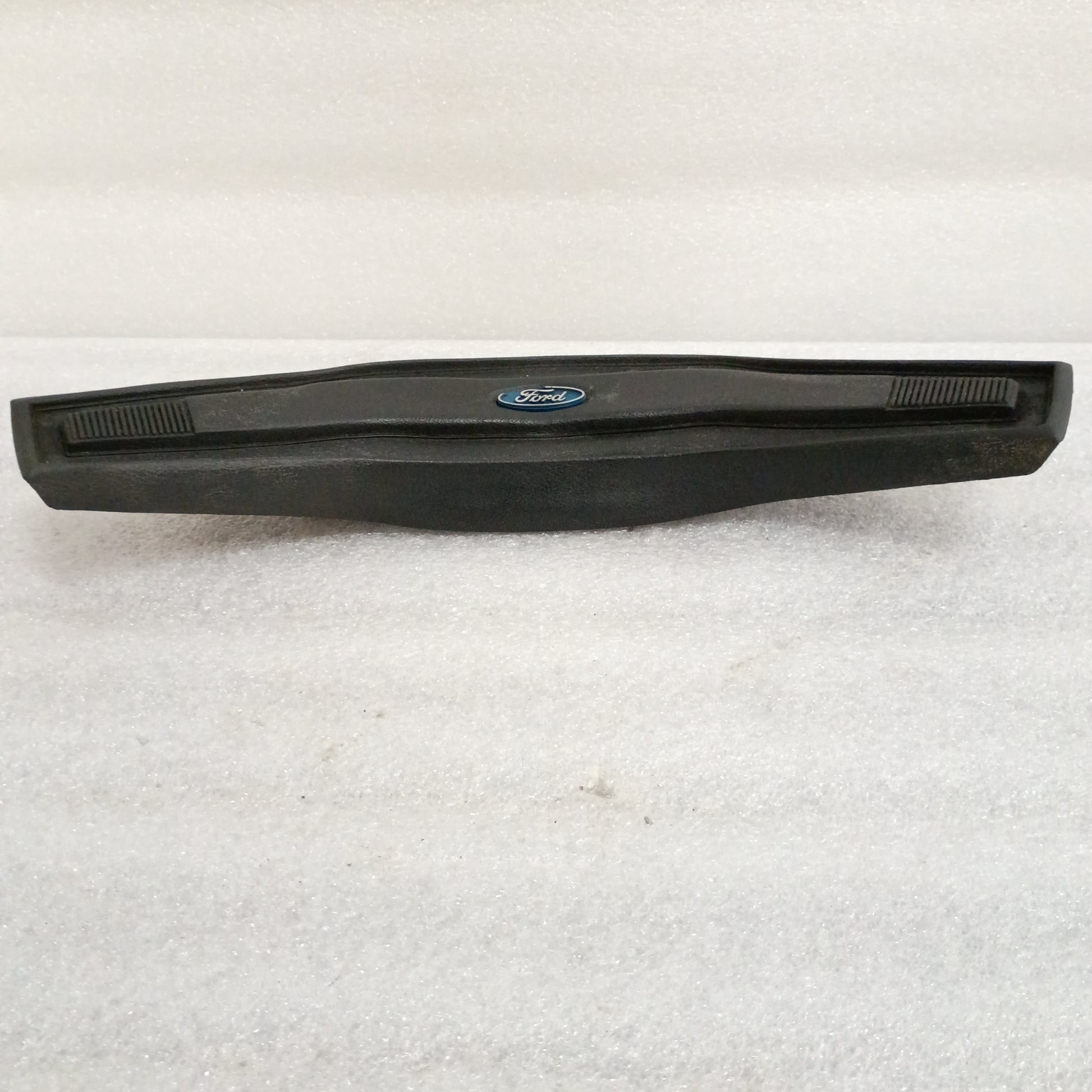 Black Ford steering wheel horn button with logo, vinyl grain pattern, slightly worn corners. Compatible with F150, F250, F350, Bronco.