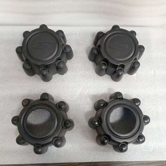 Set of four flat black Ford OEM center caps for 8 lug wheels, featuring Ford emblem. Compatible with 1999-2004 F250/F350 Super Duty.