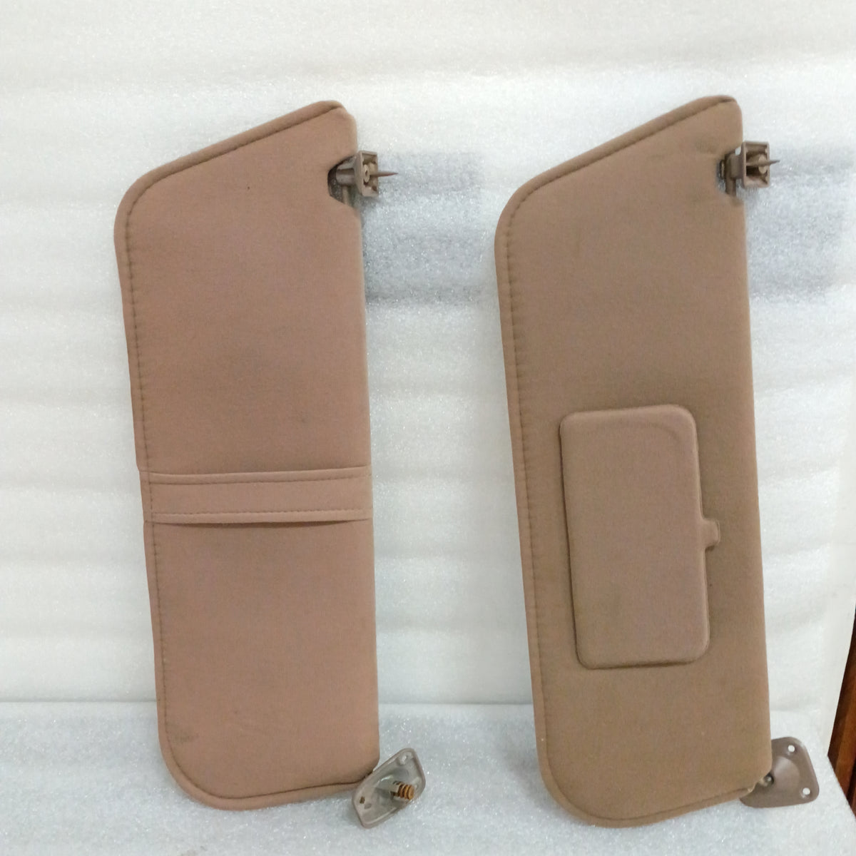 Tan cloth sun visors for Ford F-series/Bronco, with hinges. Driver's side has paper loop, passenger's has vanity mirror cover.