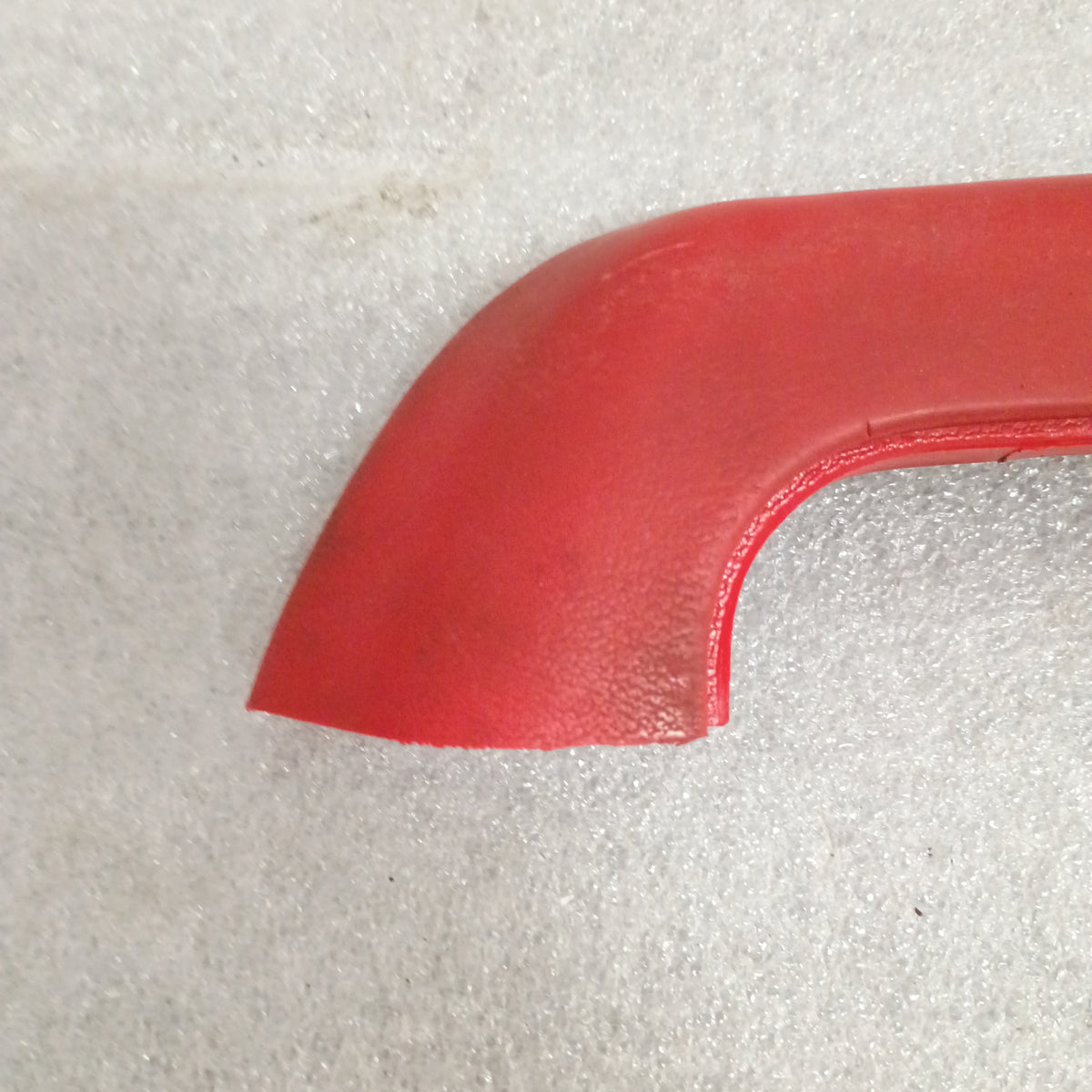 Red armrest for 1973-1979 Ford F100-F350 and Bronco, showing the corner and texture. OEM Ford part.