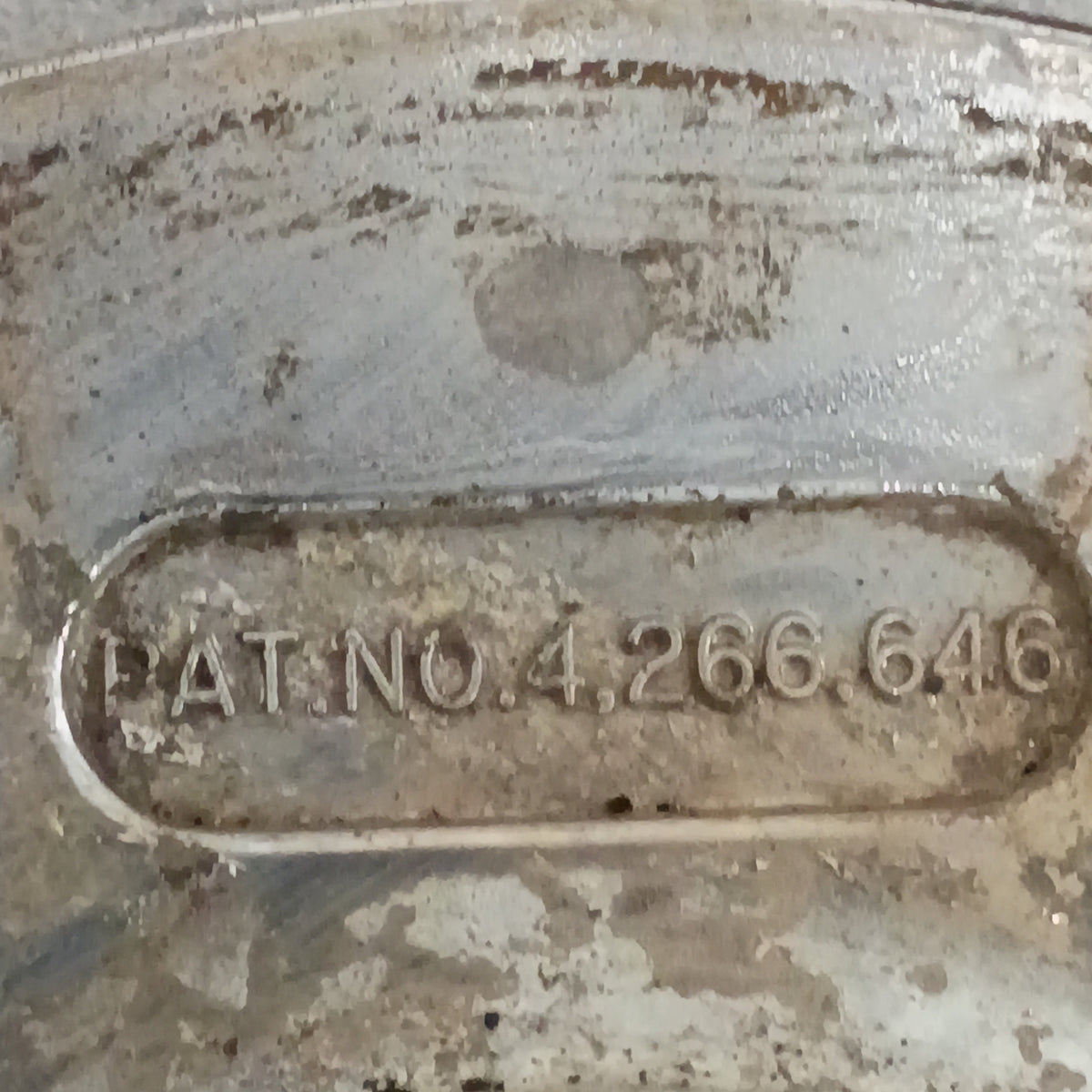 Close-up of a worn metal surface with engraved "PAT. NO. 4,266,646," linked to Ford Top Hat Manual Locking Hubs.