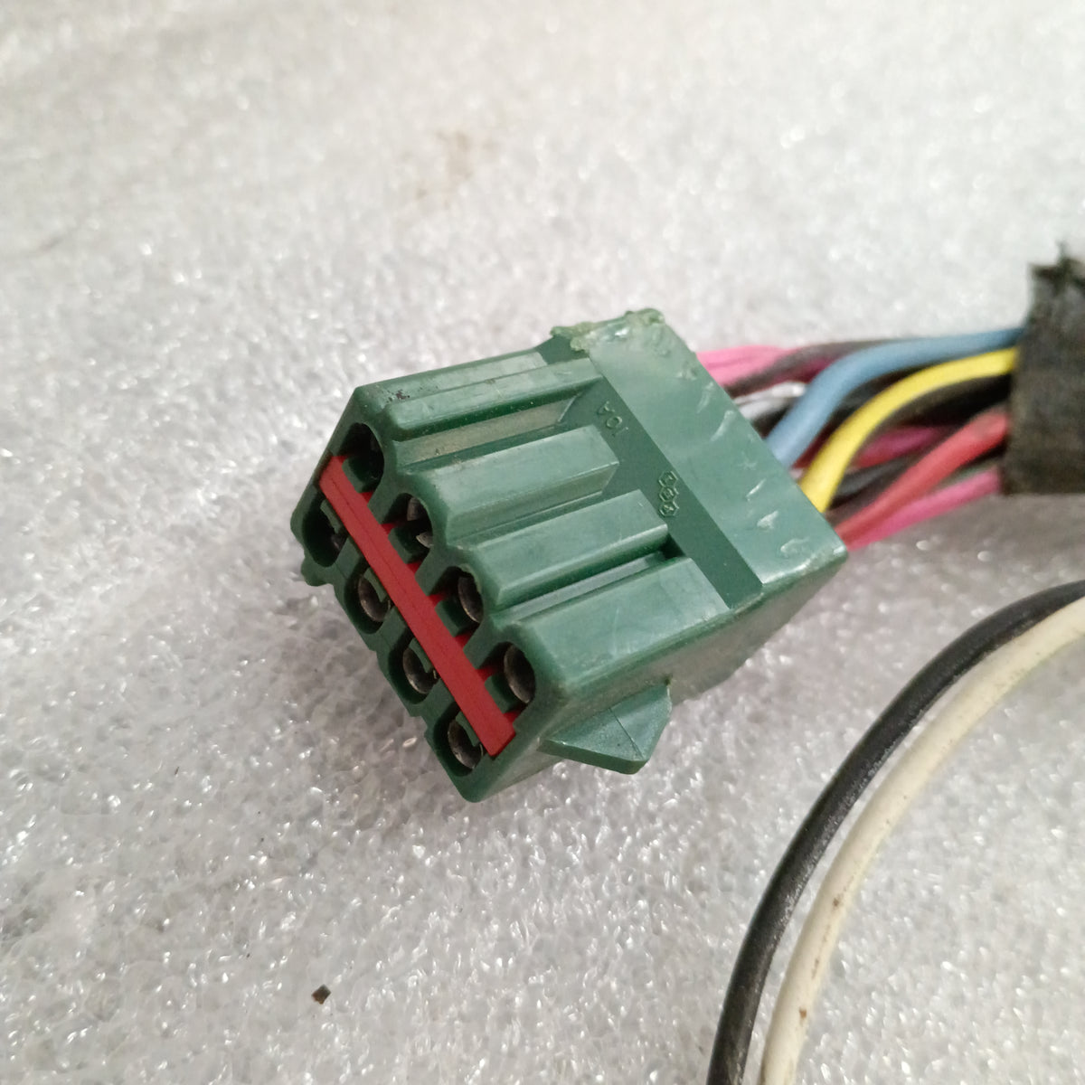 Green wire connector for Ford trucks' power window and lock systems, with multiple colored wires, on textured surface.
