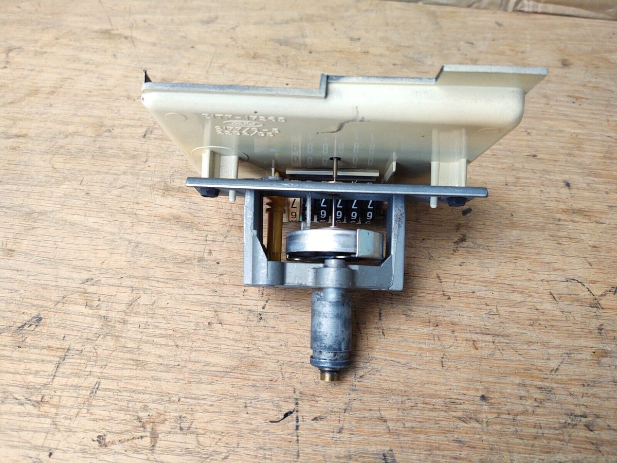 Rear mechanical assembly of a 1980-1986 Ford speedometer showing the odometer gears, metal drive connection, and cream-colored plastic housing.