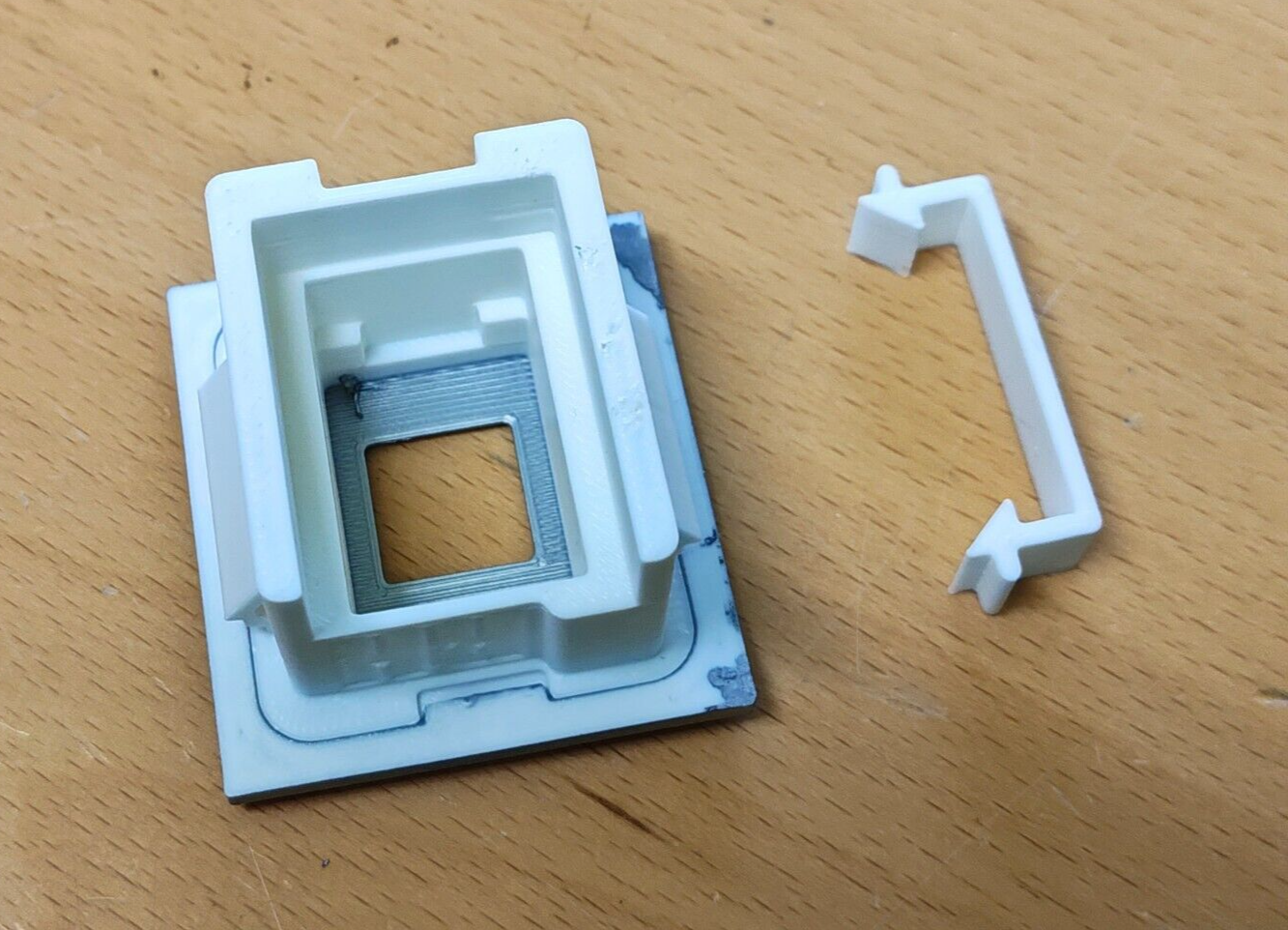 Underside view of a white passenger-side power window switch bezel and matching separate white retainer clip, compatible with 1980-1986 Ford F-Series and Bronco.