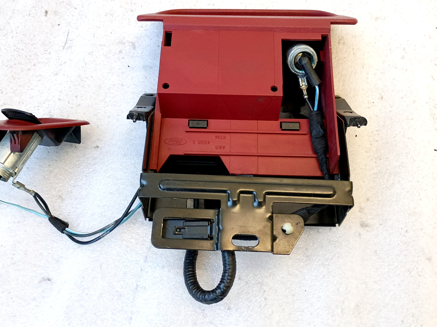 Red ashtray assembly with mounting bracket and power port for 1992-1996 Ford F-150, F-250, F-350, and Bronco. Includes refurbished wire harness.