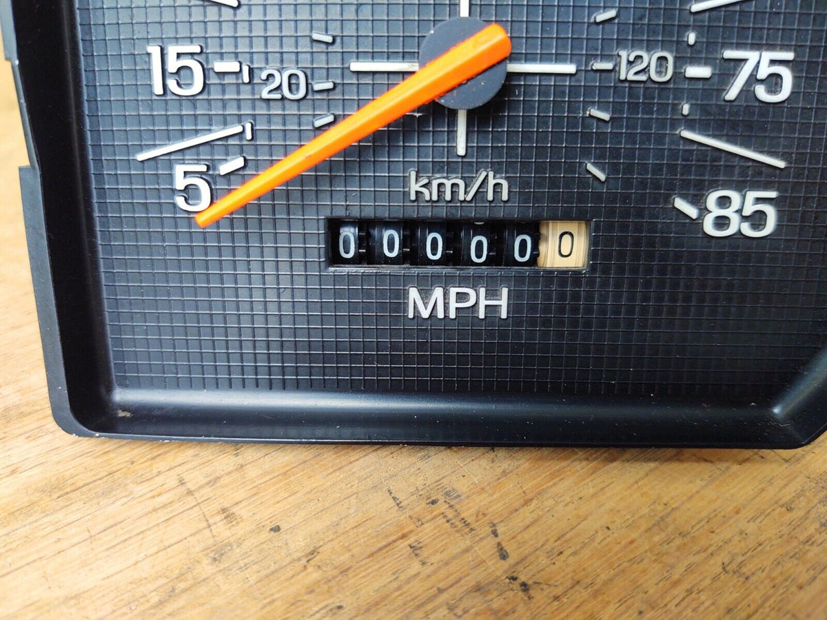 Close-up of an OEM 1980-1986 Ford F-150/Bronco speedometer showing a restored orange needle and an odometer reset to 000000 miles.