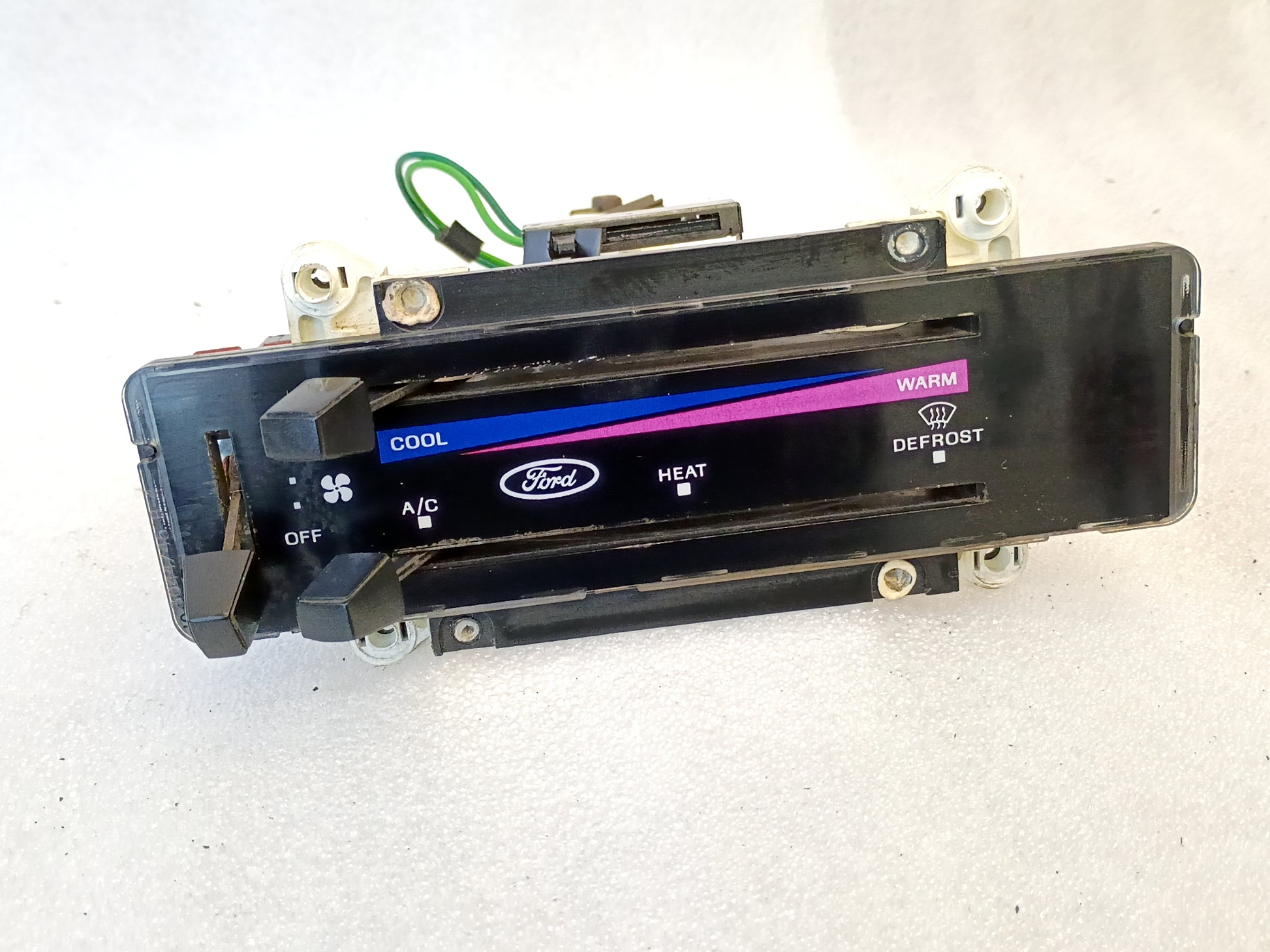 Ford OEM heater and AC control panel for 1980-1986 F-series and Bronco, featuring temp sliders and colored indicators.