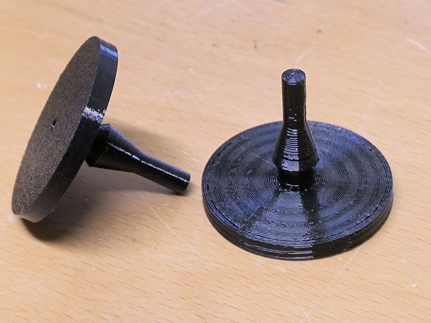 Two black rubber clutch pedal bumpers for 1980-1991 Ford F150, F250, F350, and Bronco. Each bumper features a flat circular disc with a tapered central stem, shown from different angles.