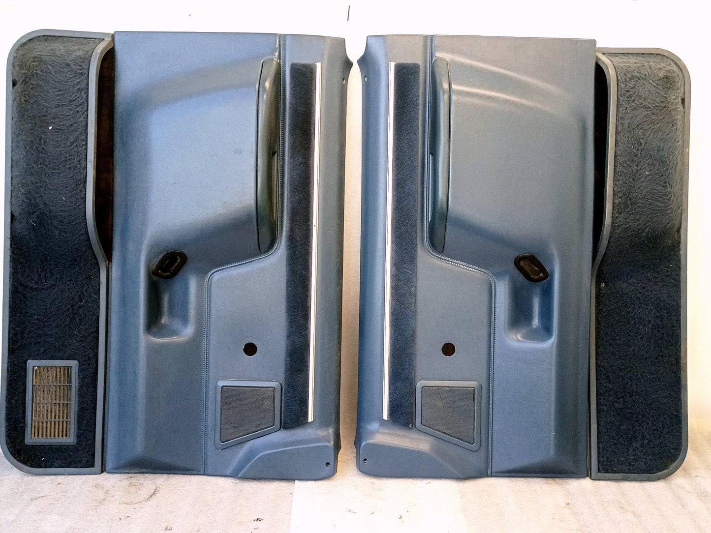 Pair of light blue door panels with manual window cutouts for Ford trucks (1987-1991). Includes speaker grills and carpeted pockets.