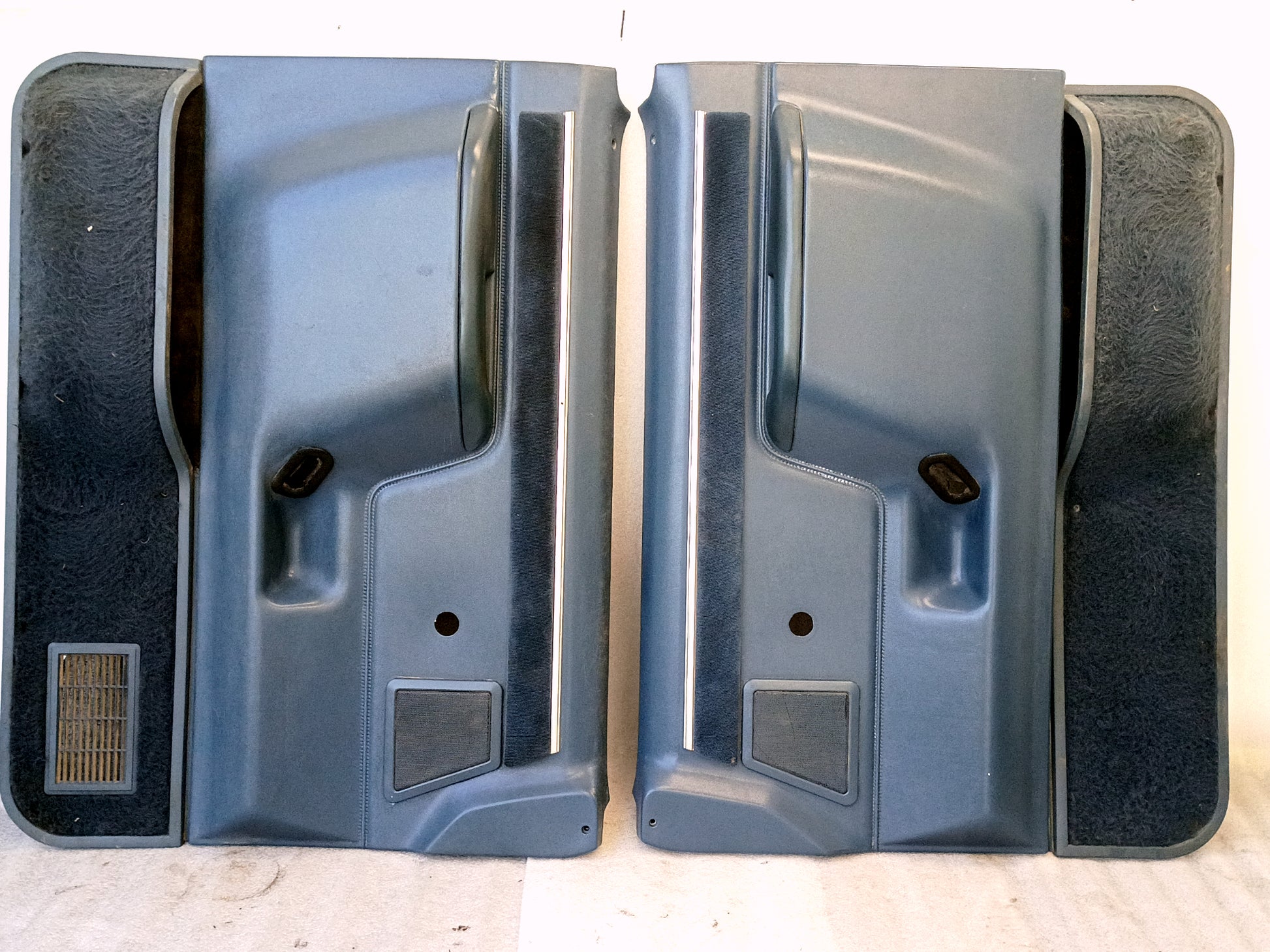 Pair of light blue door panels with manual window cutouts for Ford trucks (1987-1991). Includes speaker grills and carpeted pockets.