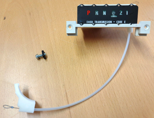 Refurbished Ford E4OD automatic transmission shift indicator with PRND21 display, attached white cable assembly, and mounting screw. Fits 1987-1991 F150, F250, F350, and Bronco models.