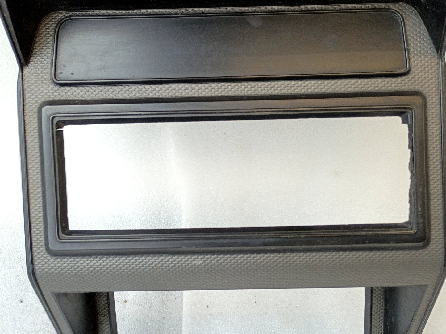 Silver radio and heater bezel for Ford F150-F350 and Bronco, single DIN slot, textured surface, fits 1980-1986 models.