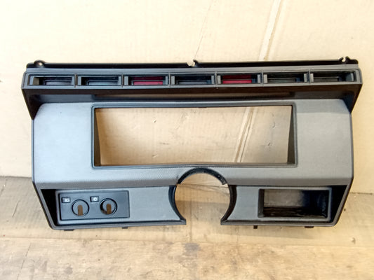 Silver gauge cluster bezel for 1980-1986 Ford F-Series and Bronco, with controls for headlights and wipers, cubby storage, and indicator lenses.