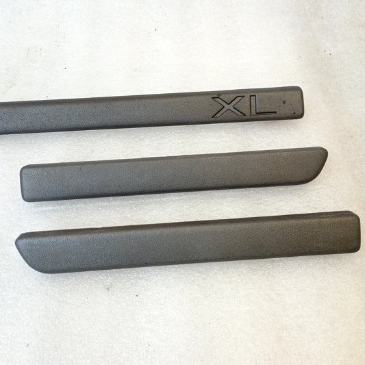 Set of three charcoal black dash trim strips for Ford F-Series and Bronco; one marked with "XL", others unmarked, OEM parts.