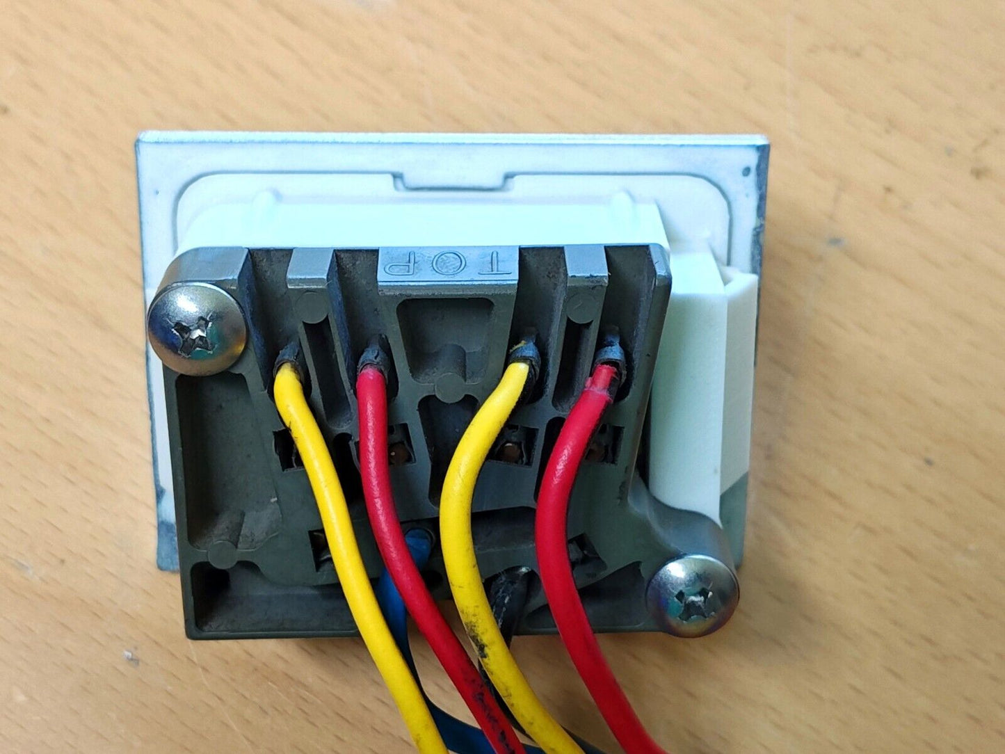 Rear view of a 1980-1986 Ford F-Series or Bronco power window bezel with the switch connector mounted using stainless screws, showing the red and yellow wires.