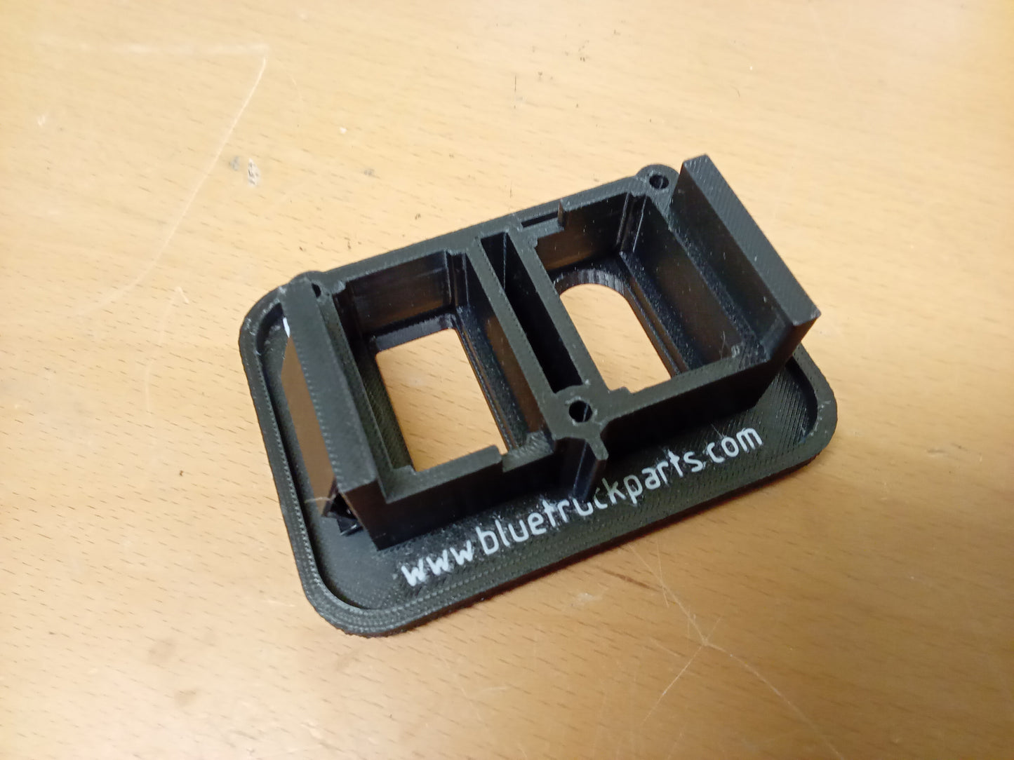 Black power window and door lock bezel for Ford trucks, with engraved URL visible, designed for 1987-1991 F-Series and Bronco.