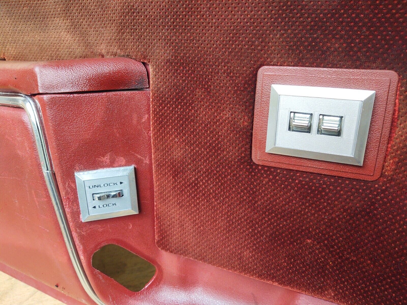 Installed left power lock bezel with chrome switch on a red door panel for 1980-1986 Ford F-150, F-250, F-350, and Bronco models, showing the 'UNLOCK' and 'LOCK' labels.